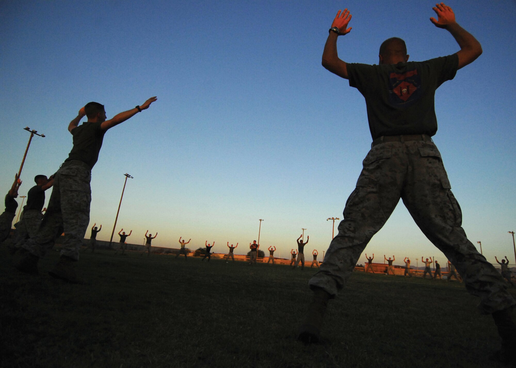 Marines and Airmen perform calisthenics during an early morning physical training session of the United States Marine Corps Corporal Course conducted at Luke Air Force Base. The mission of the course is to “provide the Marine corporal with the education and leadership skills necessary to lead Marines.” (U.S. Air Force photo/ Tech. Sgt. Jeffery Wolfe)