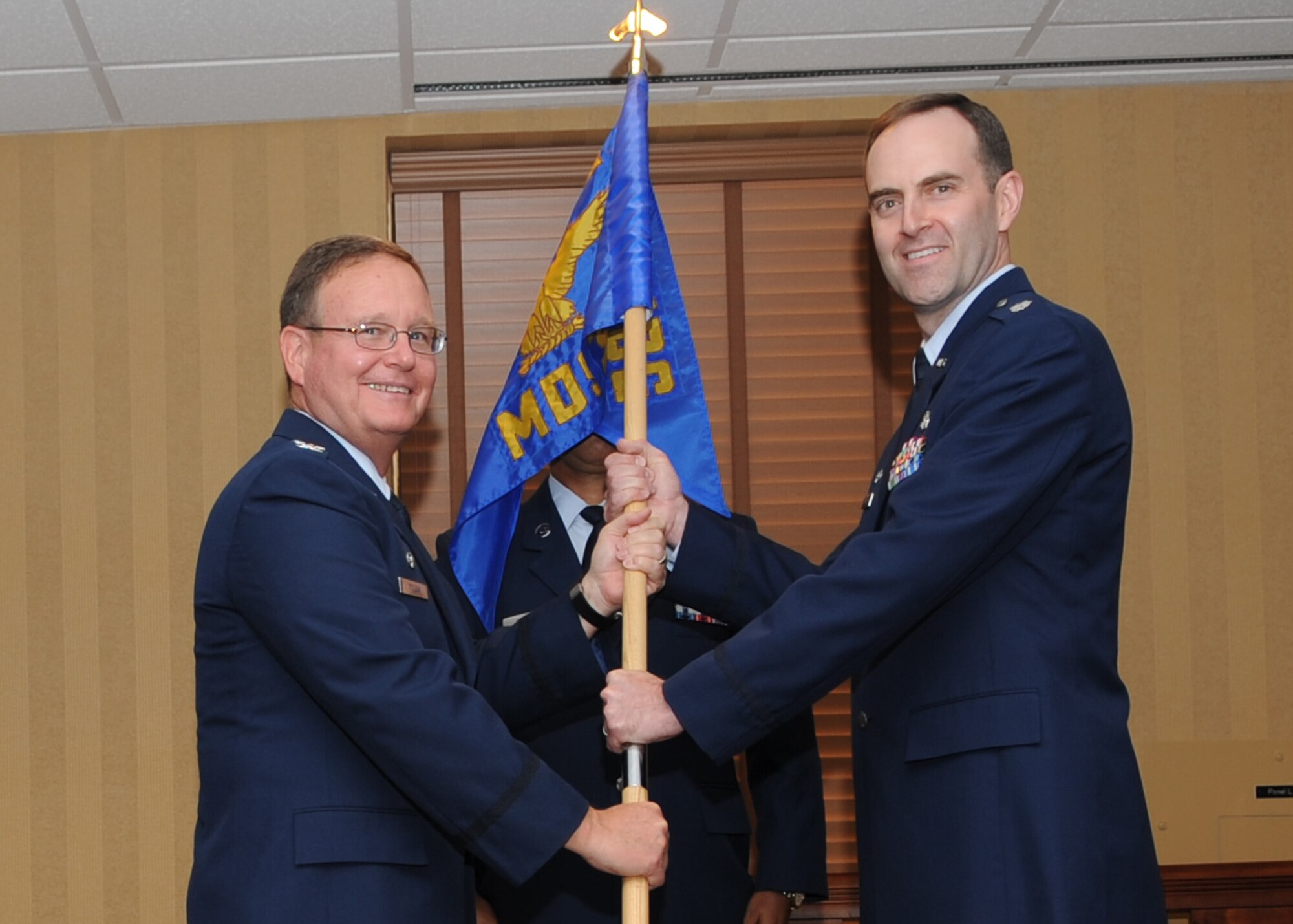 Lt. Col. Brian Wyrick receives the 355th Medical Support Squadron guidon from Col. William Pollan; 355th Medical Group commander; during the change-of-command ceremony here June 19. Colonel Wyrick assumed command of the 563rd OSS from Lt. Col. Frederick Grantham. (U.S. Air Force photo/Master Sgt. Heather Cabral)