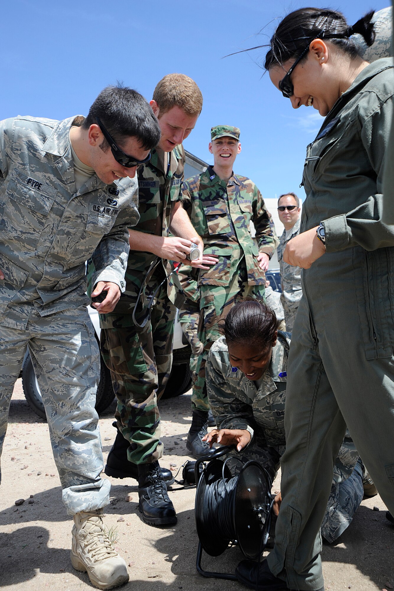 PETERSON AIR FORCE BASE, Colo.-- 21st Civil Engineer Squadron Explosive Ordnance Disposal Airmen and Air Force Reserve Officer Training Corps cadets look on as Cadet 3rd Class Jamie Hall (center) tries to reel in EOD detonating cord after an explosive demonstration near the Pete East Fire Station June 15. (Air Force photo by Craig Denton)