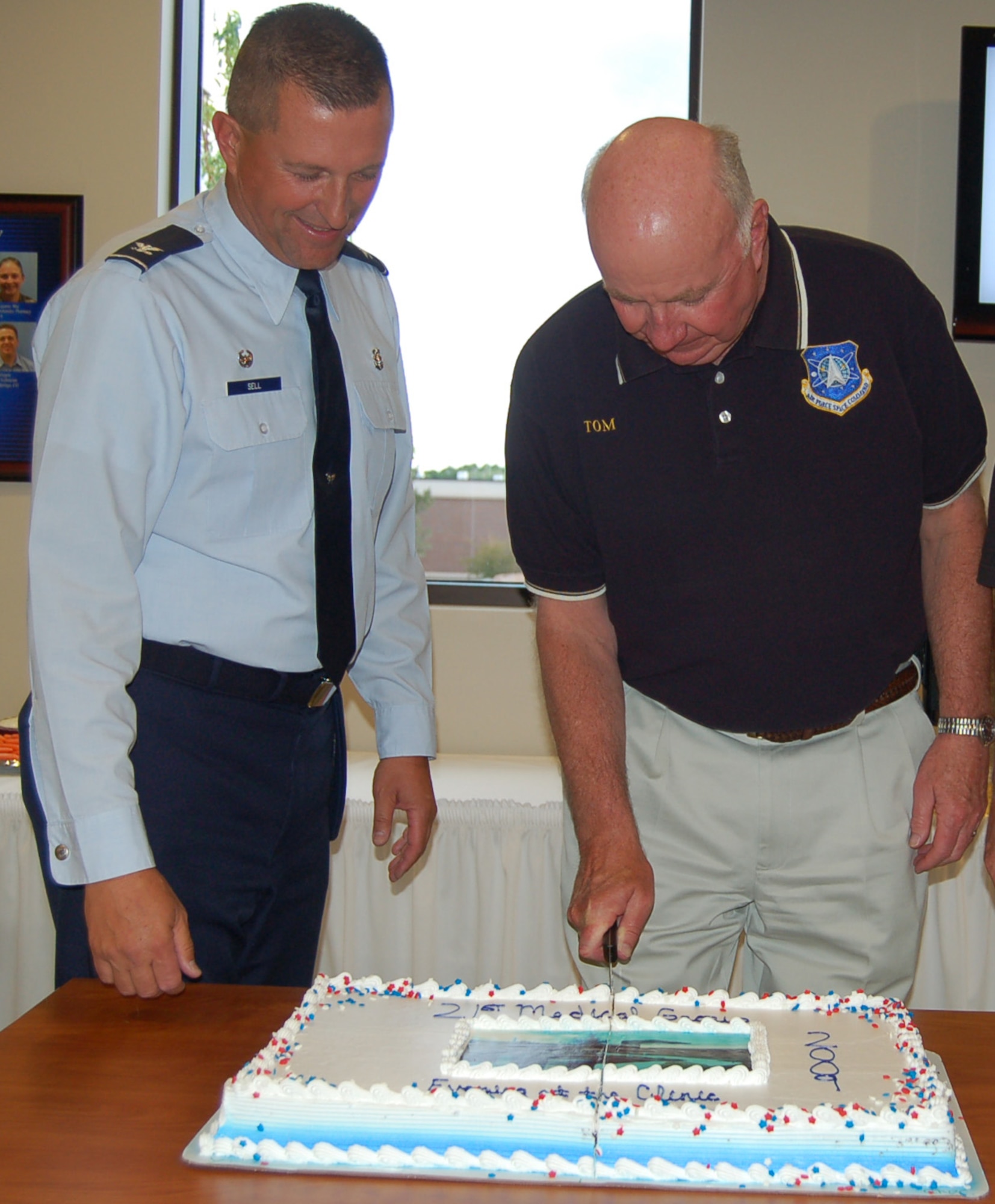 Col. John Sell, 21st Medical Group commander, and Maj. Gen. Thomas Deppe, Air Force Space Command vice commander, cut the cake during the Evening at the 21st Medical Group clinic reopening ceremony June 17. Four areas at the clinic were expanded and grew by approximately 20 percent, and the Women’s Health Clinic grew by almost 40 percent. Expanded areas include the Women’s Health Clinic, Flight Medicine and Public Health. (U.S. Air Force photo by Thea Skinner)
