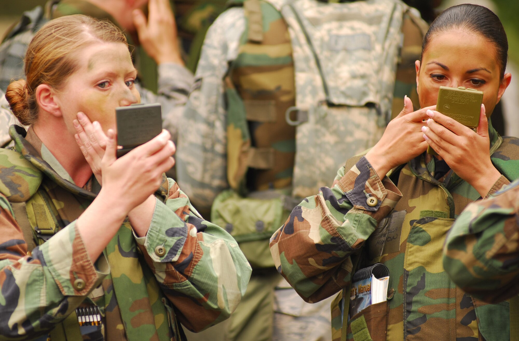 VANDENBERG AIR FORCE BASE, Calif. - Not your average make-up, Senior Airman Lacey Elko and Tech. Sgt. Kristina Higdon, both part of the 30th Space Communications Squadron, apply camouflage paint to their faces June 24 at Cocheo Park here during a North Star exercise.  Members use camouflage paint to help conceal and blend themselves into the surrounding areas. (U.S. Air Force photo/Airman 1st Class Kerelin Molina)