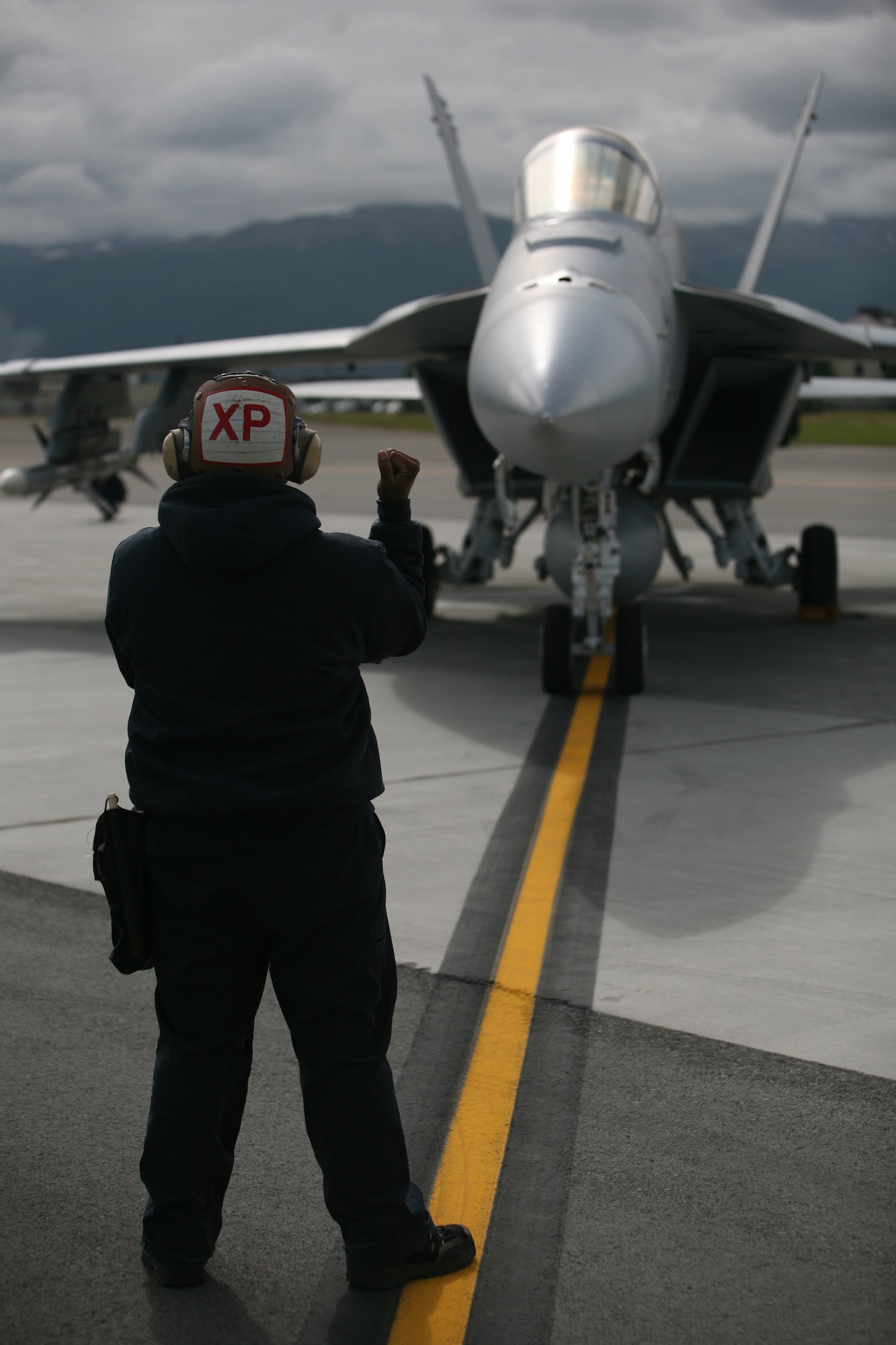 ELMENDORF AIR FORCE BASE, Alaska -- Max Carrasto, a civilian plane captain with Navy Air Test and Evaluation Squadron 9, gives hand signals to communicate with the pilot of a F/A-18E Super Hornet before it takes off from the flightline here June 19. (U.S. Air Force photo/Marine Corps Sgt. Zachary Dyer)