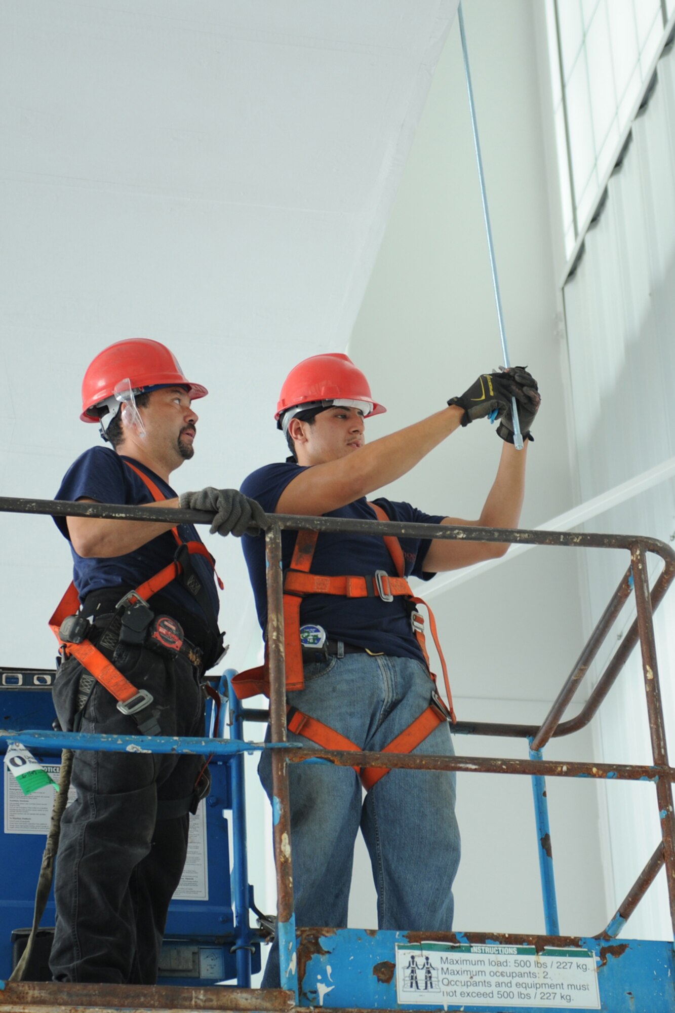 Juan Fuentes and Orlando Sotelo, pipefitters for Phoenix Fire Protection, tie a rod hanger near the flightline on Seymour Johnson Air Force Base, N.C., June 24, 2009. If a fire occurs, the rod will dispense water or foam to put out the fire in 60 seconds. (U.S. Air Force photo by Airman 1st Class Whitney S. Lambert)