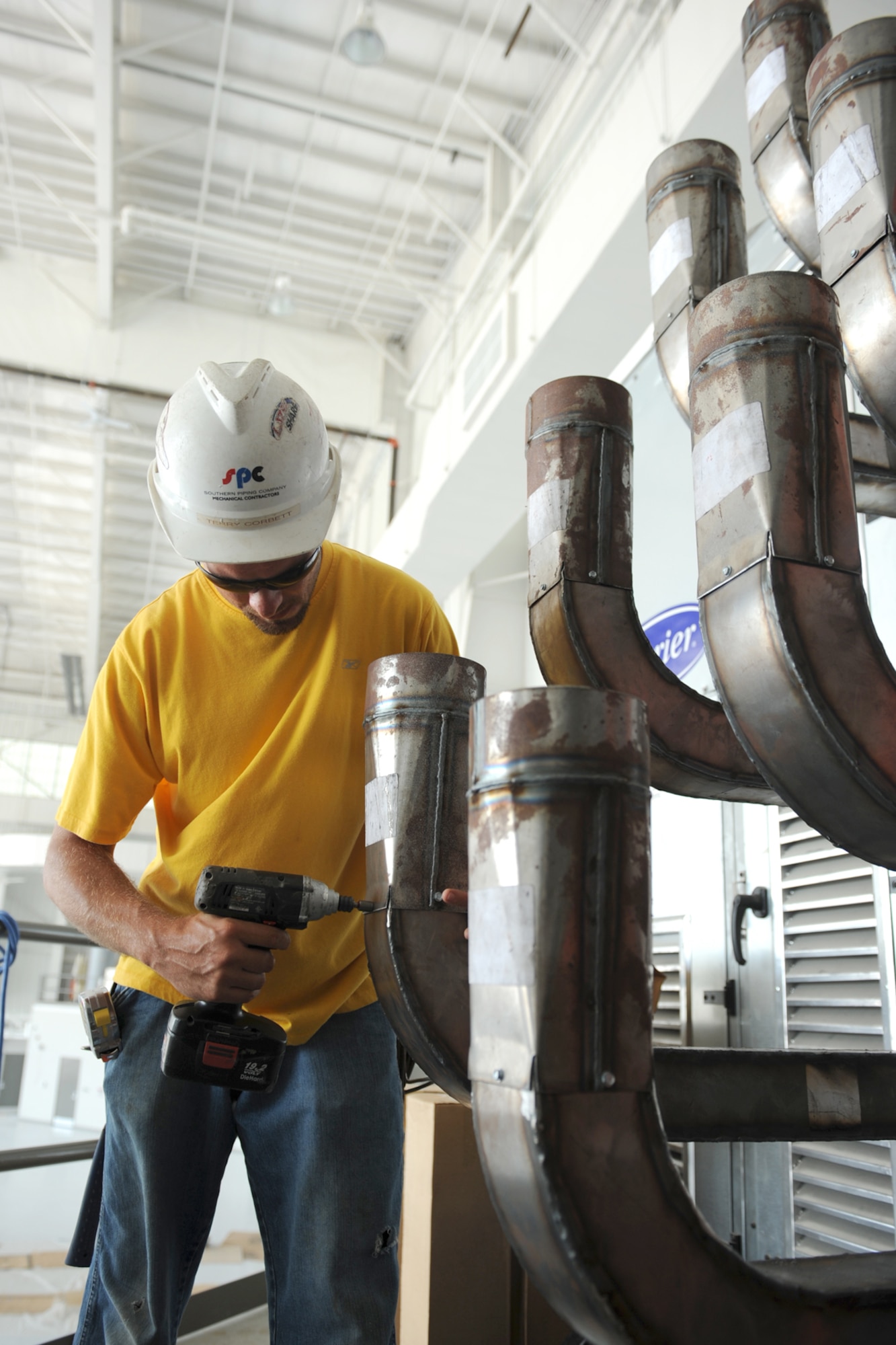Terry Corbett, heating and cooling installer for Southern Piping Company, uses an impact drill to install sheet metal near the flightline on Seymour Johnson Air Force Base, N.C., June 24, 2009. Corbett has been working with Southern Piping Company for more than two years. (U.S. Air Force photo by Airman 1st Class Whitney S. Lambert)