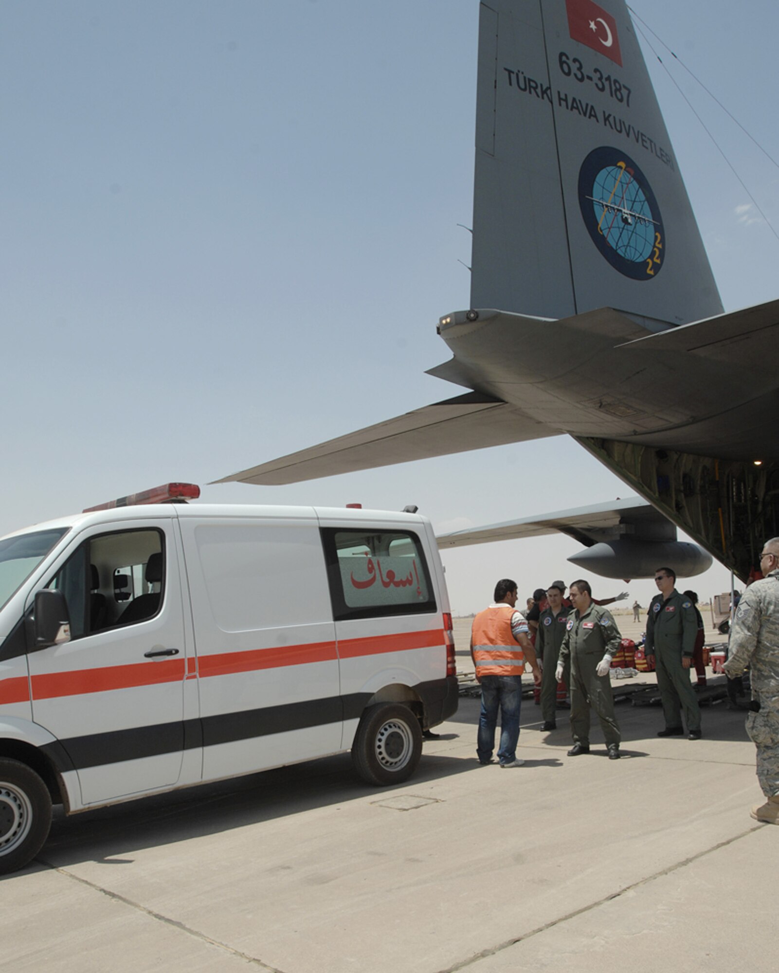 An Iraqi ambulance driver talks with a Turkish air force aircrew member at the tail of a Turkish air force C-130 before loading patients on the aircraft June 22 at Kirkuk Air Base, Iraq. U.S. and Turkish airmen, U.S. State Department and Army officials at the Kirkuk Provincial Reconstruction Team, and Turkish Red Crescent Society medical responders helped coordinate and facilitate an aeromedical evacuation to Ankara, Turkey, for 11 victims of a June 20 suicide truck bombing in Taza District south of Kirkuk city. More than 80 people were killed and 250 injured in the blast. (U.S. Air Force photo/Staff Sgt. Eunique Stevens) 
