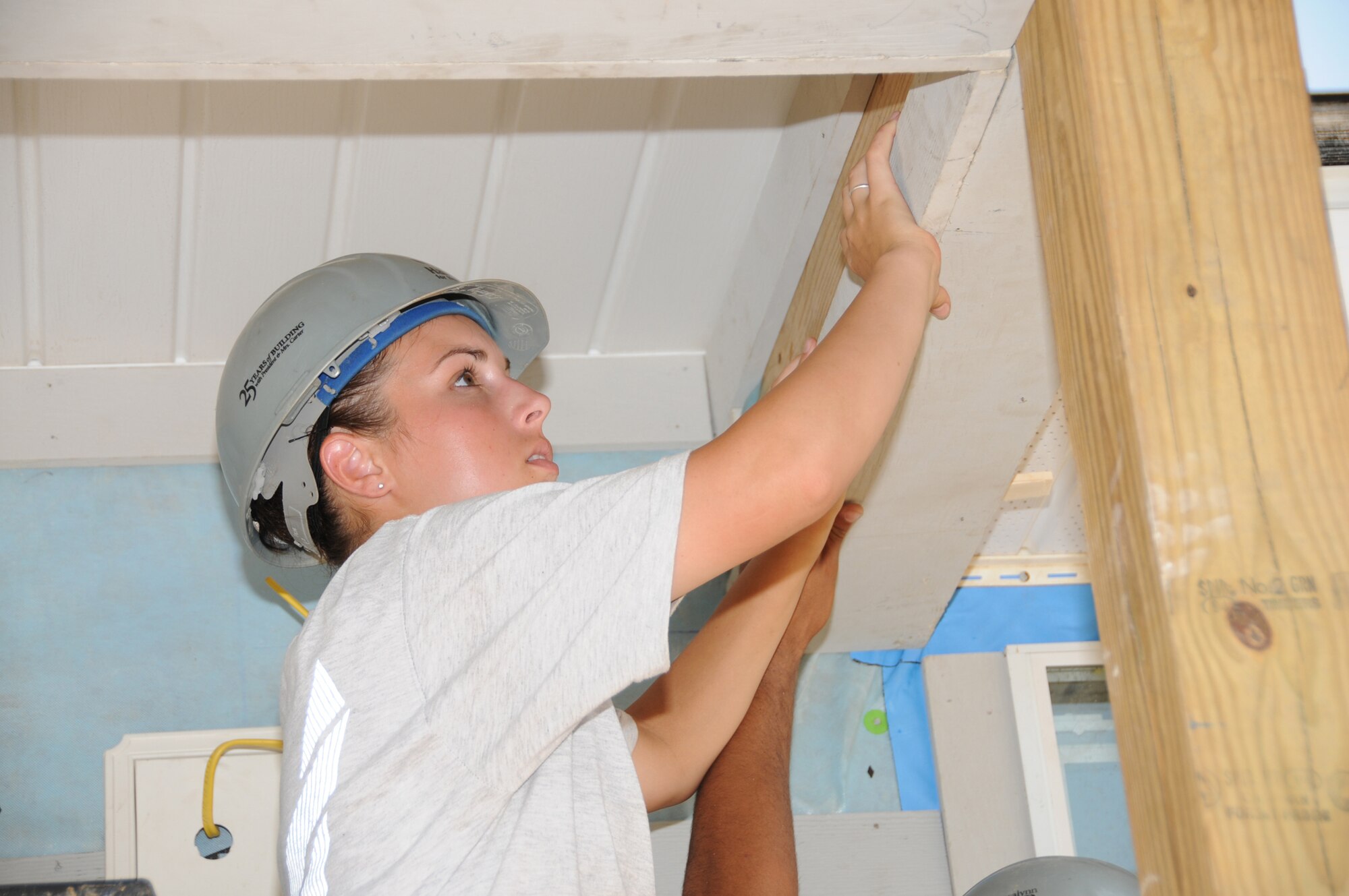 Airman Basic Ashley LaValley hangs accent framing on a side porch for a Habitat for Humanity home under construction in Gulfport.  (U.S. Air Force photo by Kemberly Groue)