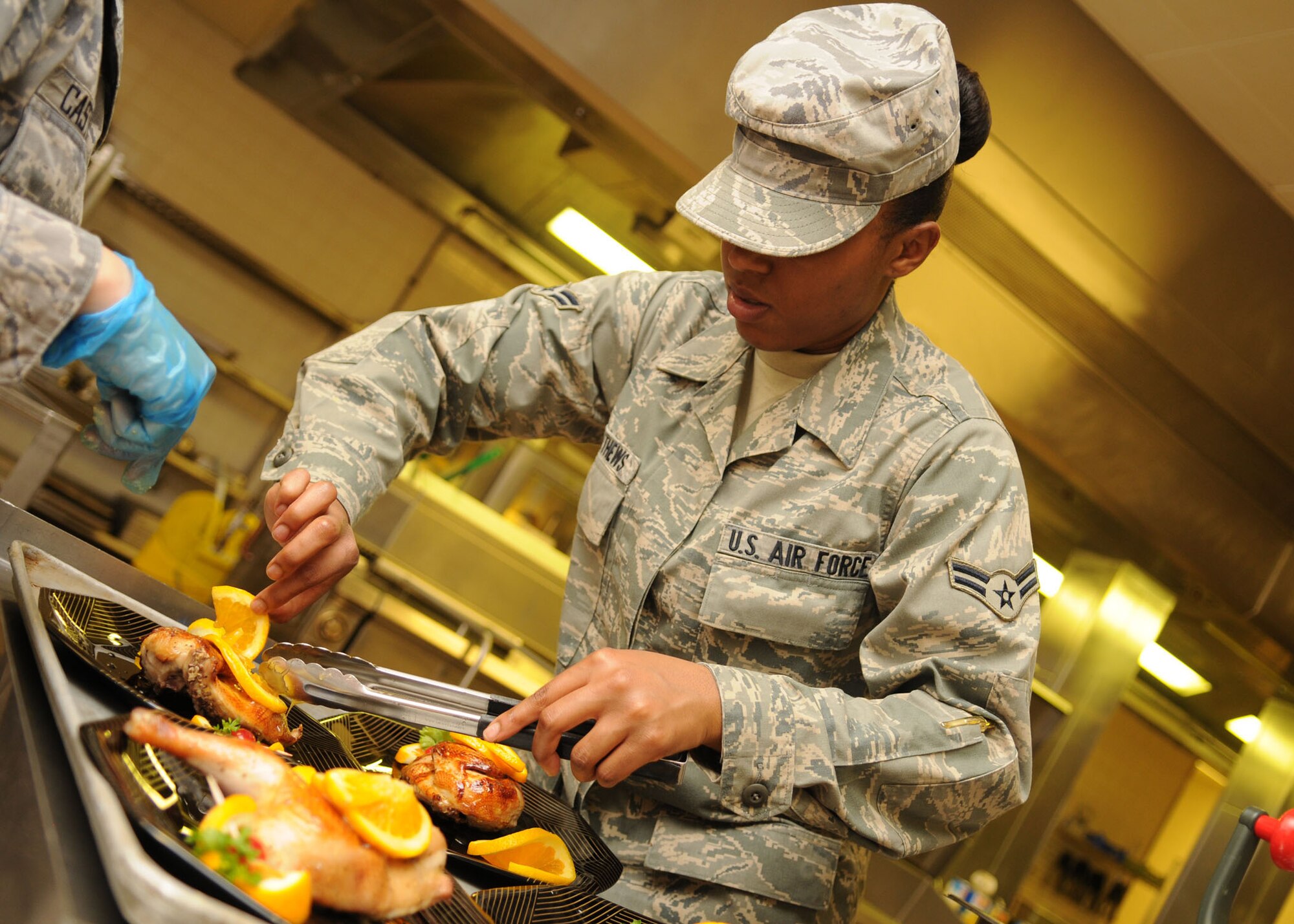 Airman 1st Class Kiara Matthews, 100th Force Support Squadron, places orange slices on her chicken in the final minutes of the Top Chef Challenge at the dining facility June 17, 2009, at RAF Mildenhall, England. Six teams had 90 minutes to prep, cook, and serve a full course meal to four judges who would determine a winner based on taste, texture and presentation. The menu dinner picked was chosen from an Air Force recipe, but allowed each chef to use their own creative talents for each dish. The winner won a trip to Ramstein Air Base, Germany, to compete against other base winners throughout United States Air Force Europe. (U.S. Air Force photo by Staff Sgt. Jerry Fleshman)