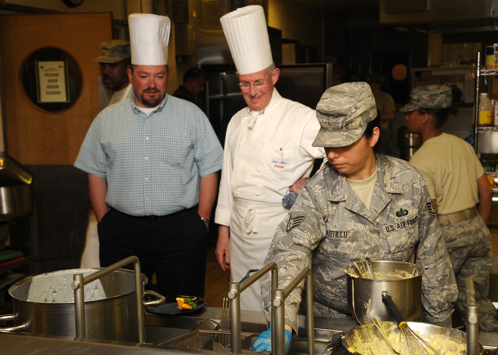 Staff Sgt. Angela Castillo, 100th Force Support Squadron, deep fries fritters during the Top Chef Challenge, while United States Air Force Europe Command Chef, Jean-Marc Laurent and Christian Peal, 100th FSS sustainment services flight chief, observe from behind June 17, 2009, at RAF Mildenhall, England. (U.S. Air Force photo by Staff Sgt. Jerry Fleshman)