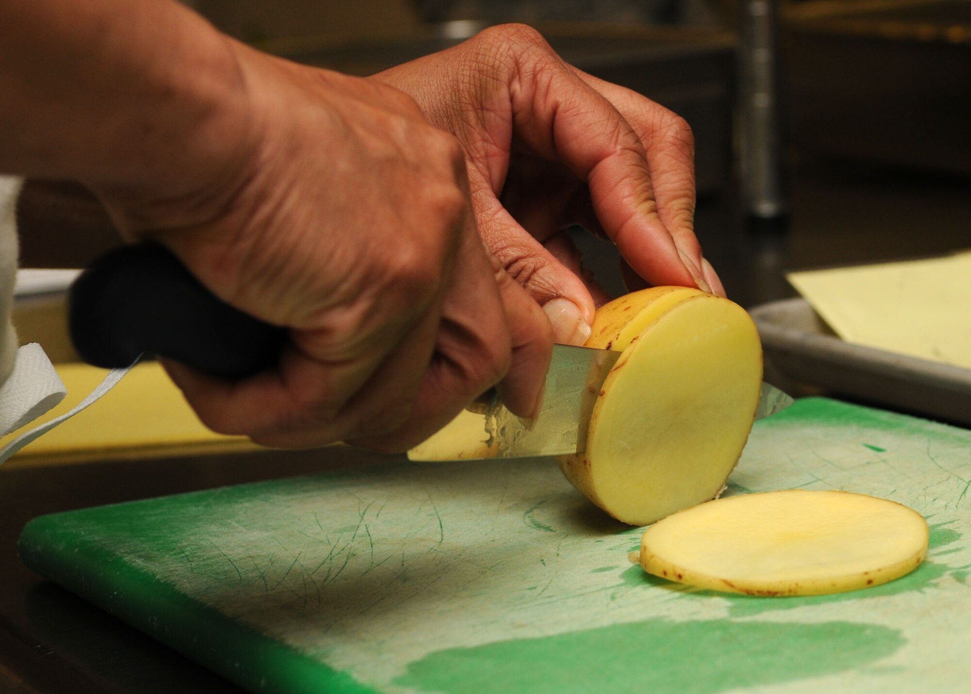 Head cook of the dining facility Rose St. John, 100th Force Support Squadron, cuts a potato into thin slices during the Top Chef Challenge June 17, 2009, at RAF Mildenhall, England. Six teams worked vigorously to prep, cook and serve an Air Force menu dinner for the opportunity to win a trip to Ramstein Air Base, Germany, to compete against other base winners throughout United States Air Force Europe. (U.S. Air Force photo by Staff Sgt. Jerry Fleshman)