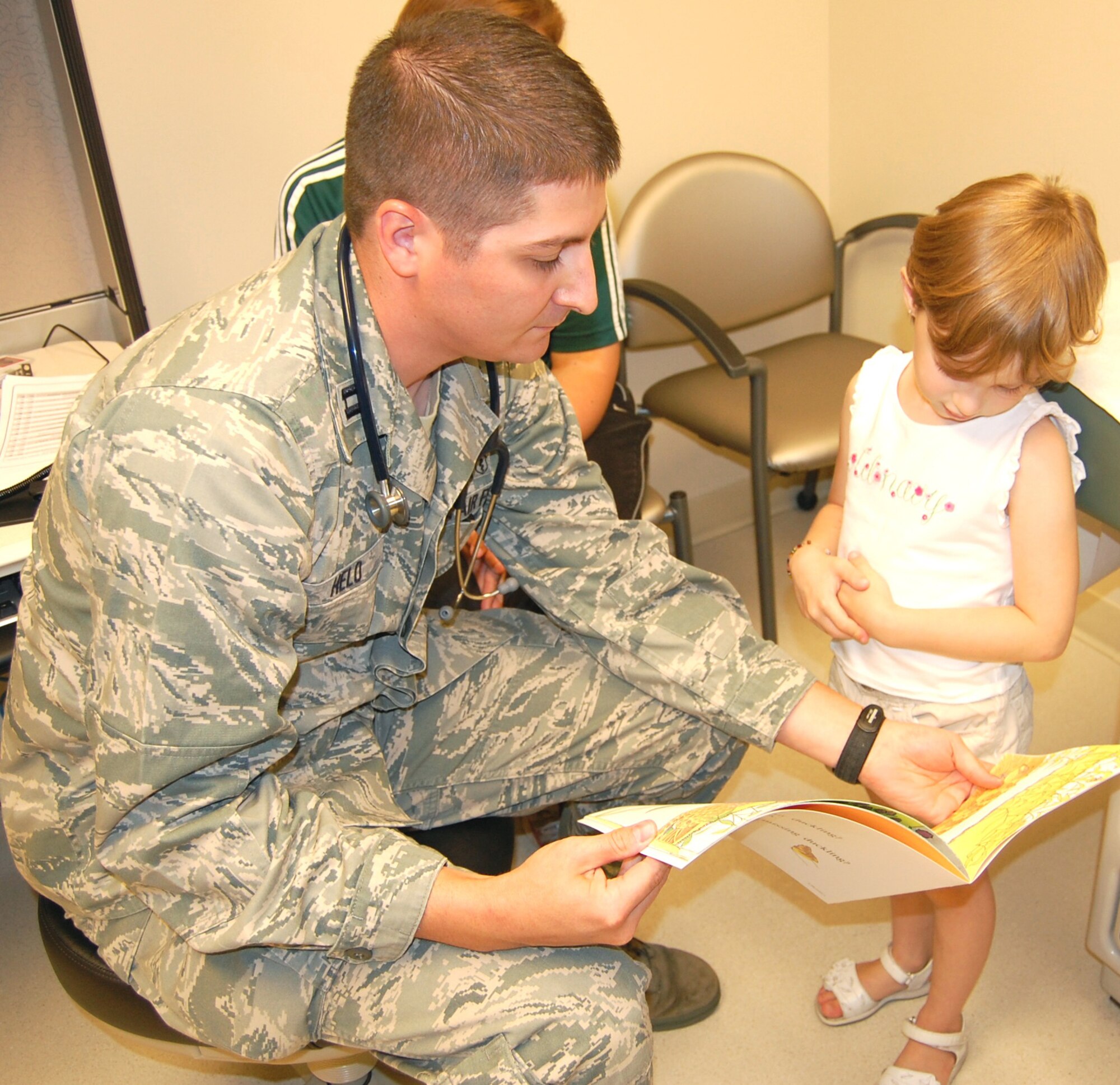 Capt. (Dr.) Kermit Helo, a pediatrician with the pediatric clinic, shows Lucy Calton, 4, a book during a recent medical appointment.  Clinic providers give books to young patients as part of the “Reach Out and Read” program.  Lucy is the daughter of Chaplain (Capt.) Garrell and Amy Calton.  (U.S. Air Force photo by Steve Pivnick)
