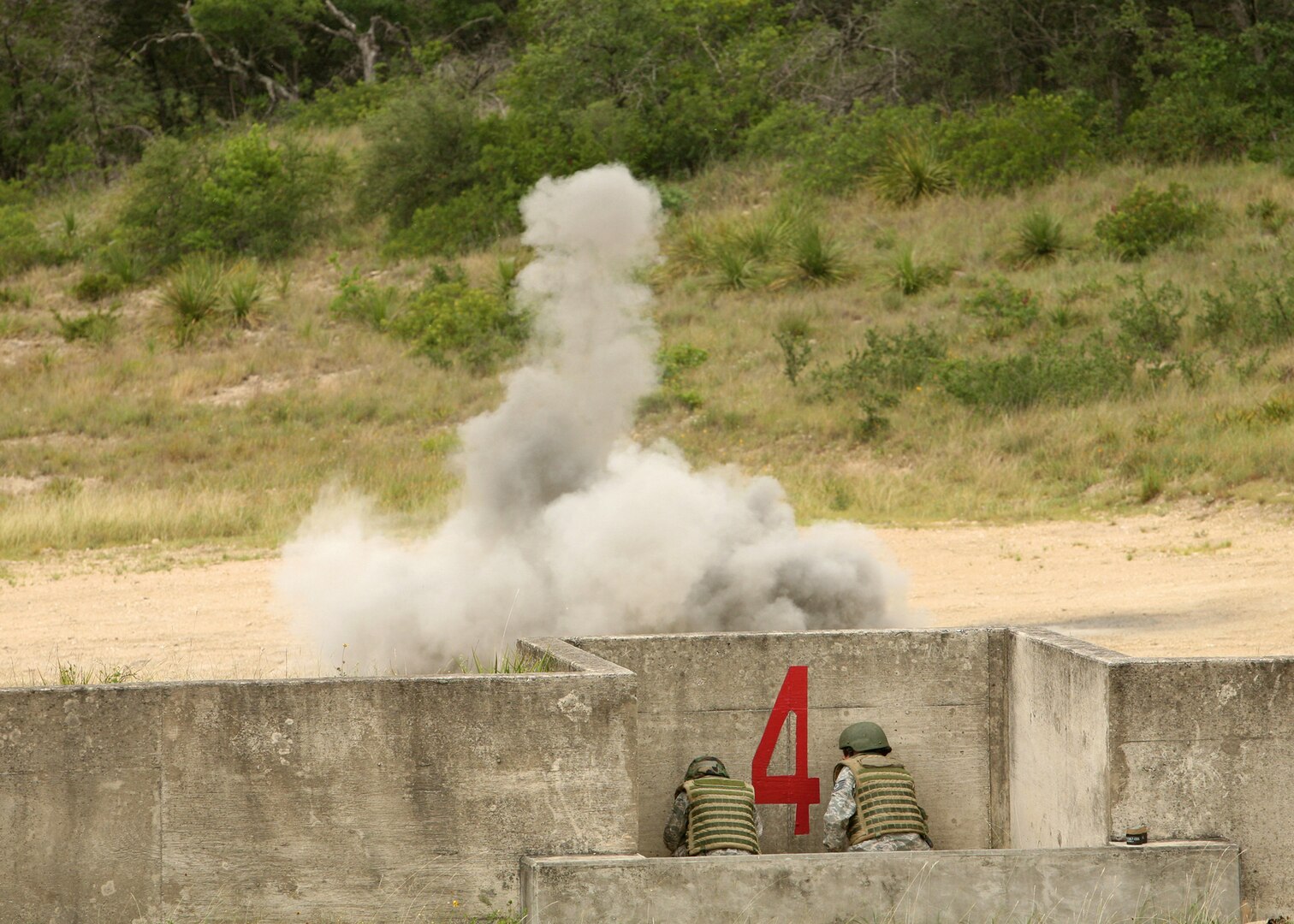A student with the  Security Forces Basic Officers' Course (left) and an instructor with the 343rd Training Squadron take cover after the student throws a live grenade June 18 at Camp Bullis, Texas. The students also detonated claymore mines during training.   (U.S. Air Force photo/Robbin Cresswell)