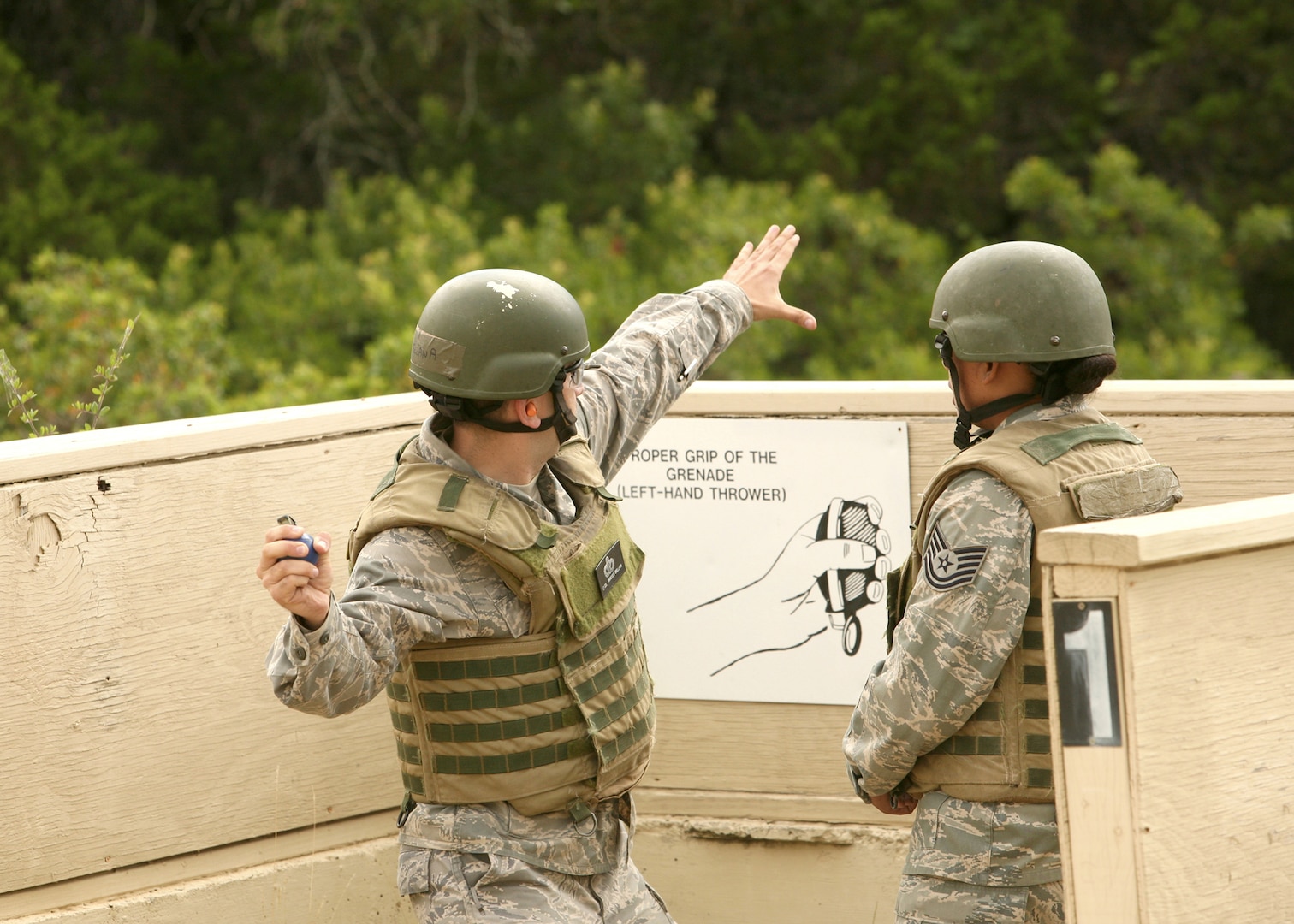 Lt Col. Francisco Orellana prepares to throw an M-67 simulator grenade as instructor Tech. Sgt. Kerissa Rivas observes June 18 at Camp Bullis, Texas.  Students are evaluated by their instructors before moving on to live ordnance. Colonel Orellana is a student in the  Security Forces Basic Officers' Course.  (U.S. Air Force photo/Robbin Cresswell)