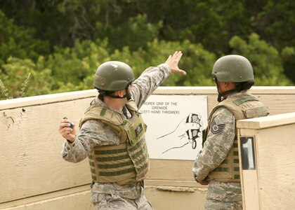 Lt Col. Francisco Orellana prepares to throw an M-67 simulator grenade as instructor Tech. Sgt. Kerissa Rivas observes June 18 at Camp Bullis, Texas.  Students are evaluated by their instructors before moving on to live ordnance. Colonel Orellana is a student in the  Security Forces Basic Officers' Course.  (U.S. Air Force photo/Robbin Cresswell)
