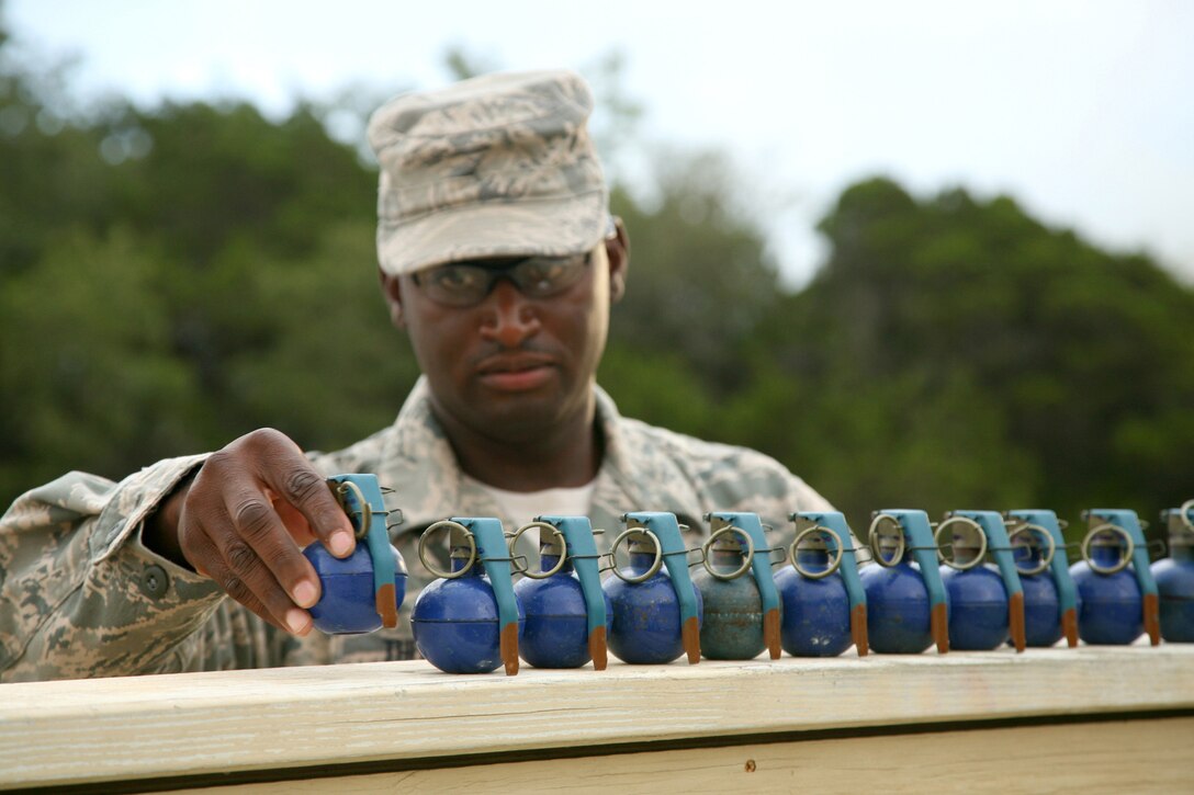 Tech. Sgt. Eric Thomas, an instructor with the 343rd Training Squadron, preps M-67 training grenades June 18 at Camp Bullis, Texas.  Students practice throwing the simulated grenades to hone their technique as instructors evaluate before moving on to live ordnance. (U.S. Air Force photo/Robbin Cresswell)