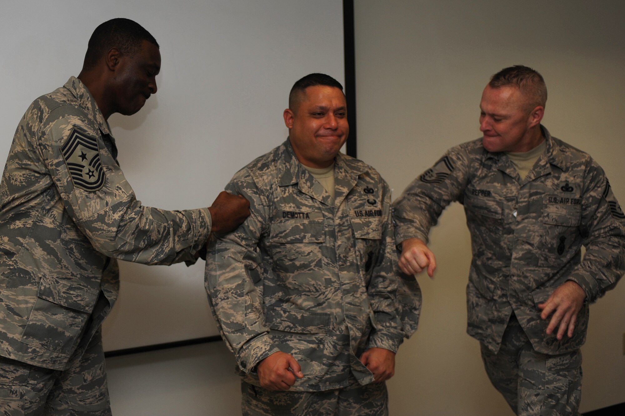 Chief Master Sgt. Fitzgerald Hentz, U.S. Air Force Expeditionary Center command chief, and Senior Master Sgt. Scott Pepper, 421st Combat Training Squadron superintendent, tack technical sergeant stripes on Staff Sgt. Daniel Demotta, also with the 421st CTS, on June 18 at the center.  Twelve Airmen from the Expeditionary Center were selected for E-6 stripes. (U.S. Air Force Photo/Staff Sgt. Nathan G. Bevier) 