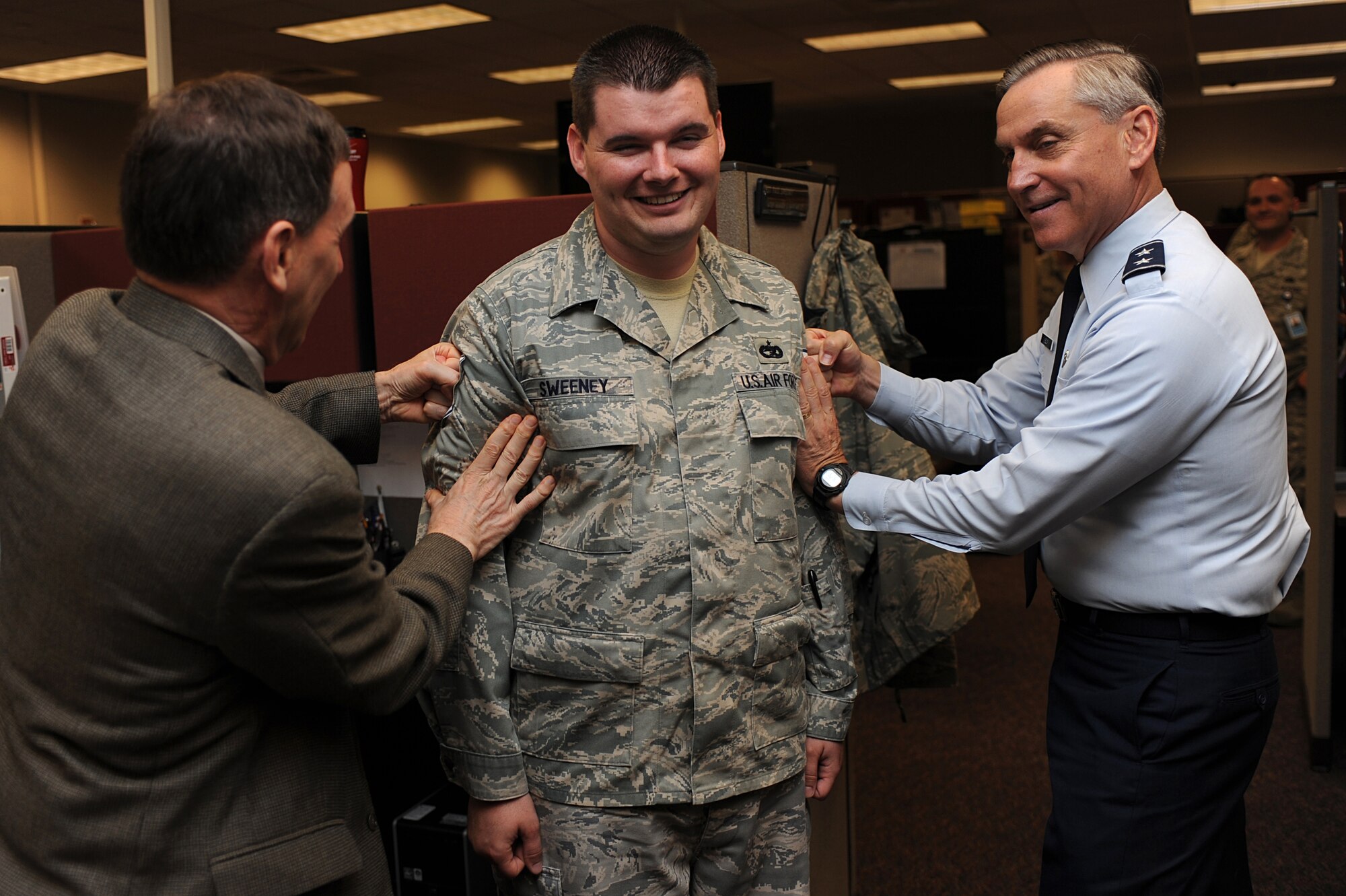 Major Gen. Kip Self (right), U.S. Air Force Expeditionary Center commander, and Mr. Rudy Becker, Mobility Operations School, tack technical sergeant stripes on Staff Sgt. Paul Sweeney, also with the MOS, on June 18 at the center.  Twelve Airmen from the Expeditionary Center were selected for E-6 stripes. (U.S. Air Force Photo/Staff Sgt. Nathan G. Bevier) 