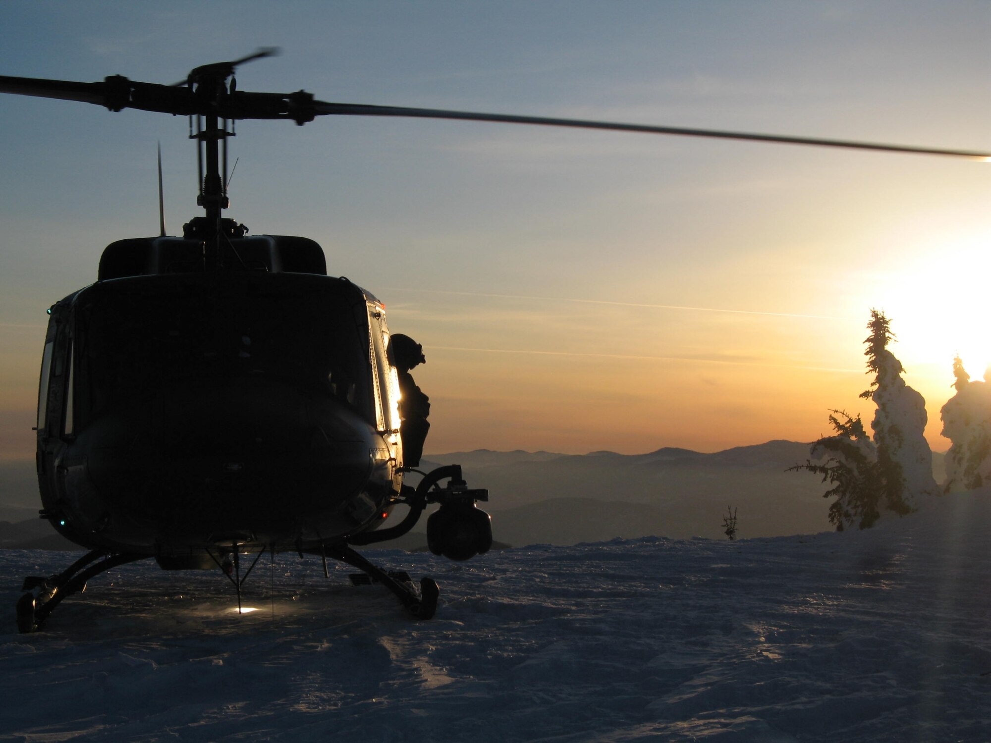 A UH-1N Huey on the top of Calispel mountain in the Northern Survival Training Area with the sunset in the background. (U.S. Air Force photo/Staff Sgt. Jacob Bragg)