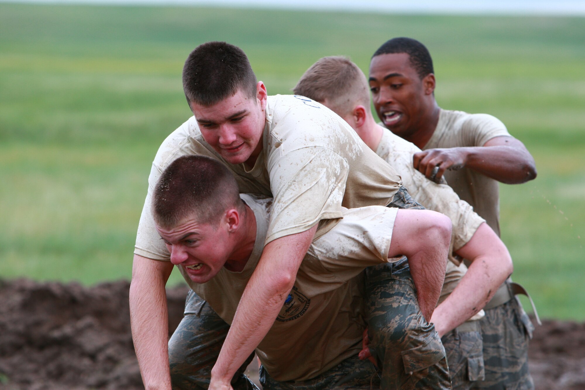 Airmen 1st Class Adam Thomas, Patrick Currie, Marcus Hamilton and Staff Sgt. Corey Wright, all from the 90th MSFS, participate in the Team Pain portion of the Crow Creek Challenge. For the fireman carry part of Team Pain, two teammates carry the other two back into the mud pit for more four-man push ups. The person who does the carrying switches every cycle, so the entire team's physical fitness is evaluated.