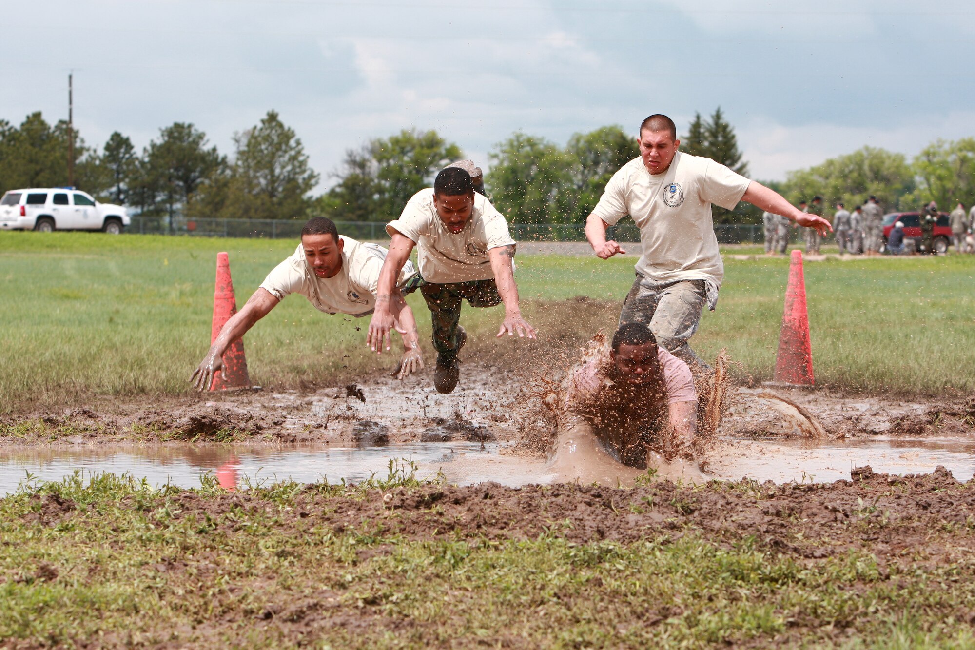 F.E. WARREN AIR FORCE BASE, Wyo. - Airman 1st Class Enrique Manley, Staff Sgt. LaRue Jackson, Senior Airman Charleston Williams and Airman 1st Class Miguel Ferreira, all from the 90th Security Forces Squadron, dive into the mud for the Team Pain Portion of the Crow Creek Challenge June 11. (Photos by Jeff Allred.)