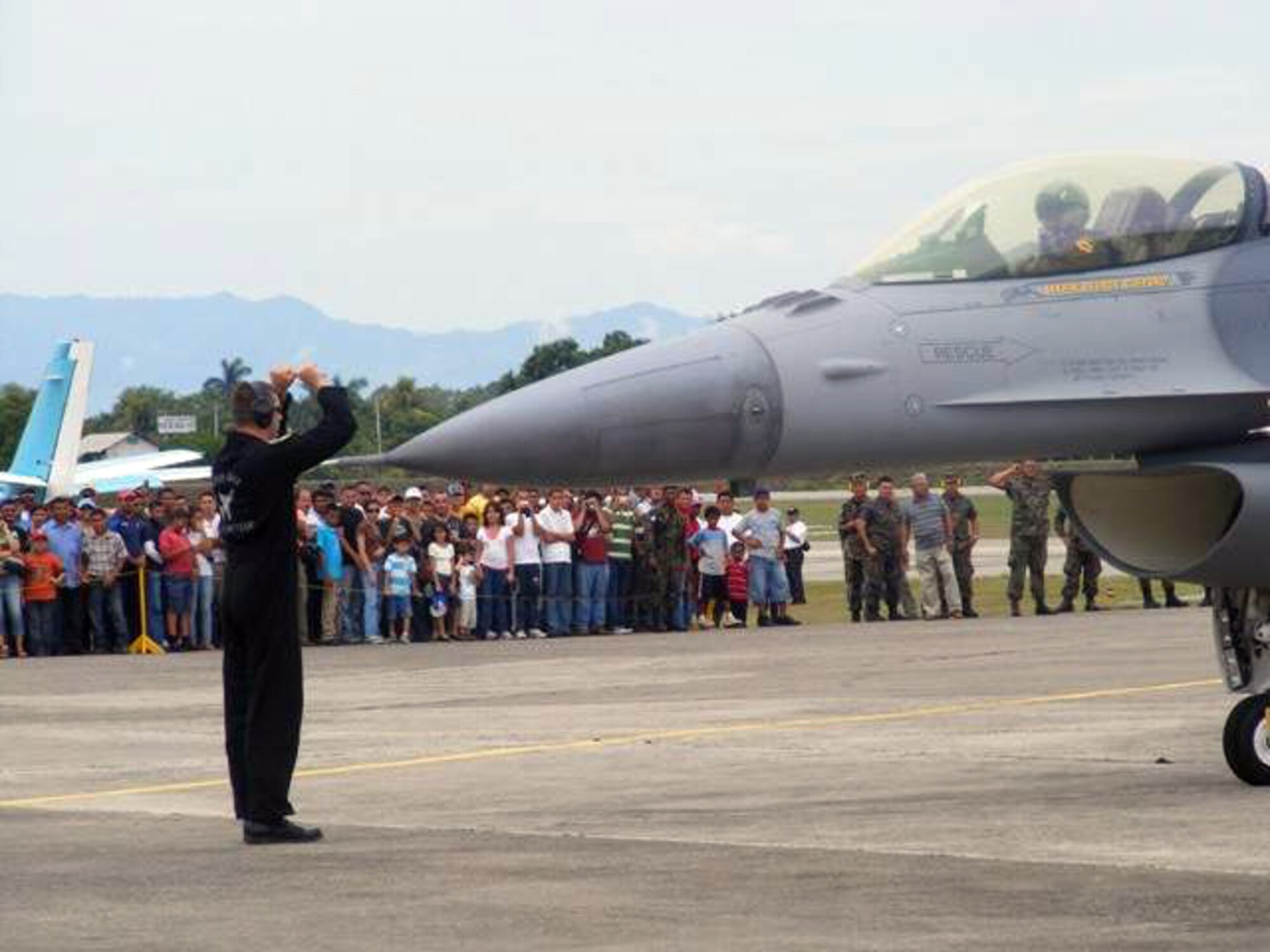 A crowd of airshow attendees cheer as a crew chief from the Viper East F-16 Demonstration Team marshals an F-16 Fighting Falcon after an aerial demonstration June 21 at San Pedro Sula, Honduras. More than 30 Airmen participated at the international airshow. (U.S. Air Force photo/Capt. Candace Park) 
