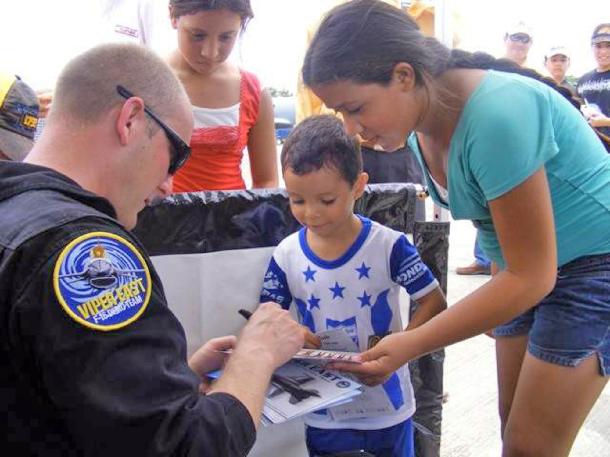 Master Sgt. Bryan Spangler signs an autograph for a Honduran boy June 20 at San Pedro Sula, Honduras. More than 30 Airmen participated at the international airshow. The more than $35,000 proceeds from the show will help build a children's intensive care unit at a local hospital. Sergeant Spangler is a Viper East F-16 Demonstration Team team chief. (U.S. Air Force photo/Capt. Candace Park) 
