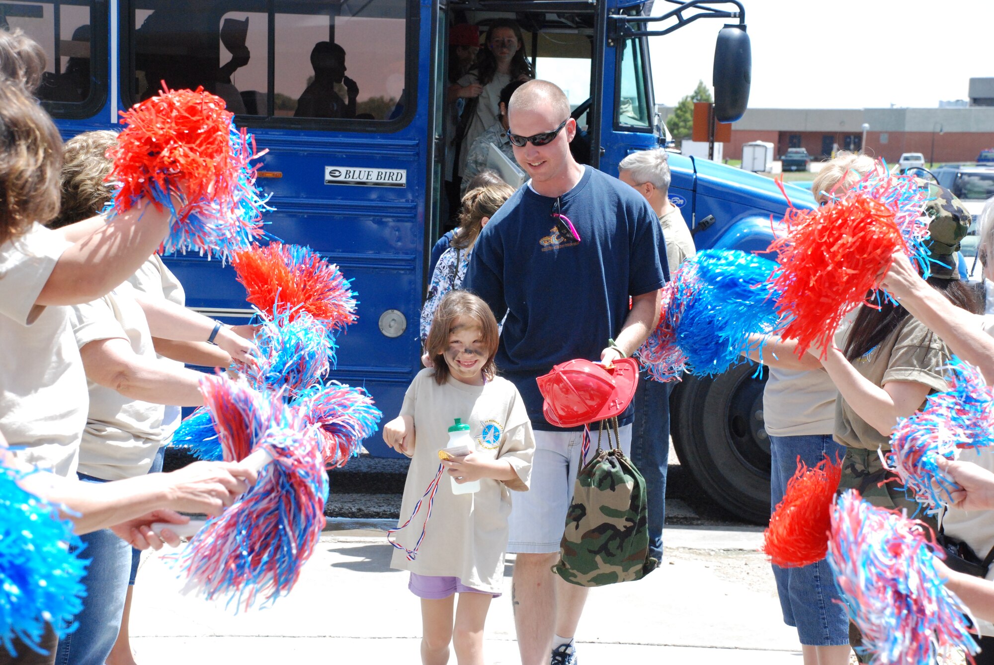 Harmonie King and her father depart the bus for the return-home party at the Warren Youth Center Saturday. Youth center staff greeted the children with red, white and blue pompoms with patriotic music playing in the background. 