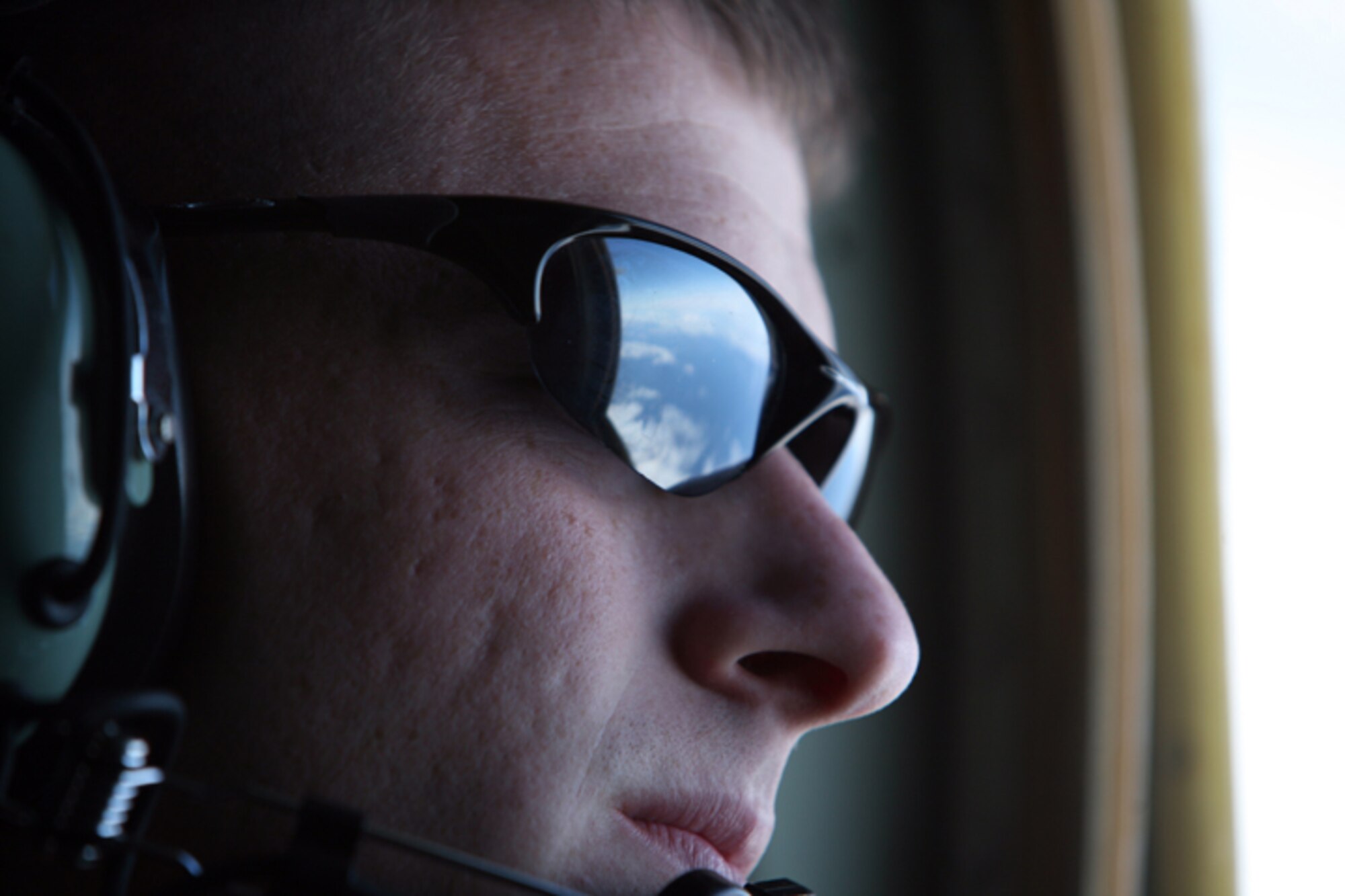 ELMENDORF AIR FORCE BASE, Alaska -- The deep blue sky of Alaska reflects in the sunglasses of Cpl. Joshua Balbontin, a loadmaster with Marine Aerial Refueler Transport Squadron 152, as he peers out of the observation window of a KC-130J during an aerial refueling mission June 22. (U.S. Air Force photo/Marine Corps Sgt. Zachary Dyer)