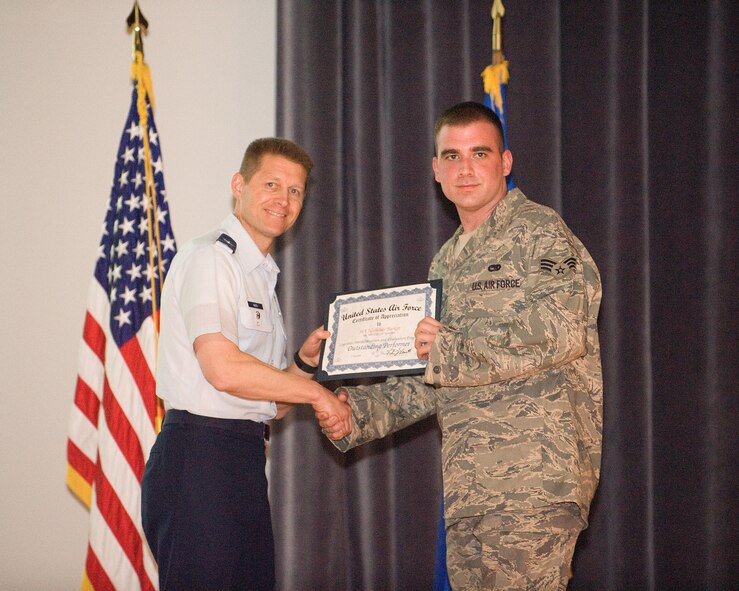 Col. Thomas Kauth, Logistics Assessment Branch chief, presents Senior Airman Nicholas Barker, 436th Aircraft Maintenance Squadron crew chief, a certificate of appreciation for his excellence during Dover Air Force Base's Logistics Standardization and Evaluation Program inspection. Less than two months later, Airman Barker shone his excellence again by subduing an irate foreign man on an international commercial flight to Italy. The Airman kept the plane secure until it landed and the man was turned over to Italian authorities. (U.S. Air Force Photo/Tom Randle) 