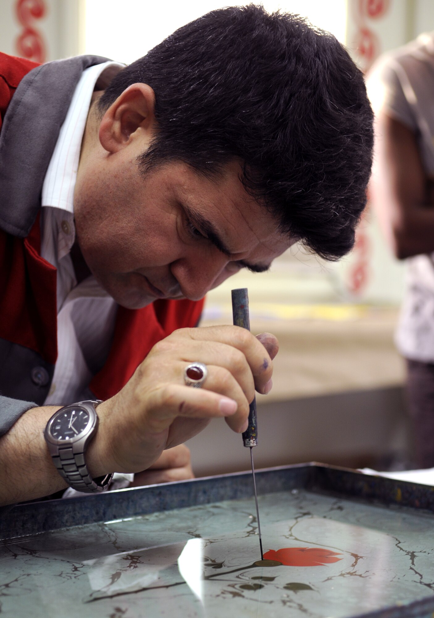 Mesut Dikel, an Ebru art instructor, demonstrates how to create a flora design during a class Wednesday, June 24, 2009 at the Arts and Crafts Center here.  Mr. Dikel has been creating Ebru art, a unique Turkish art form, for nearly 24 years.  Ebru, or paper marbling, has been practiced in Turkey since the 15th century and uses all-natural products, from the brushes to the paints.  The center plans to offer the class monthly.  (U.S. Air Force photo/Staff Sgt. Raymond Hoy)
