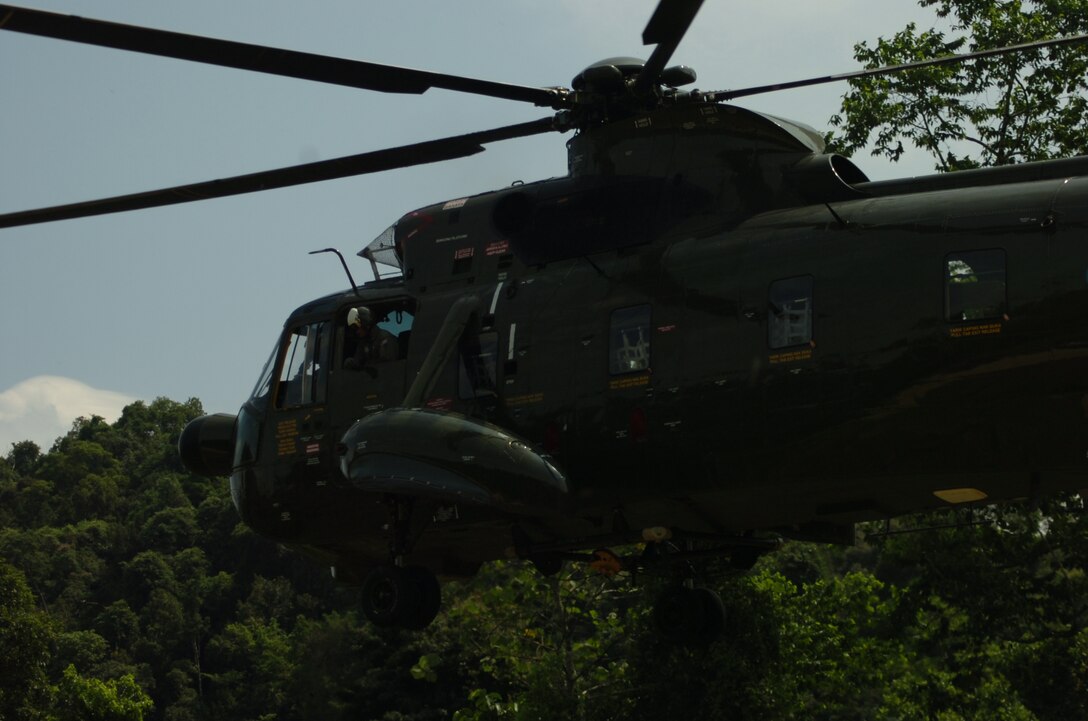 A Royal Malaysian Air Force Sikorsky SH-3 Sea King helicopter lowers itself onto the the landing zone to pick up RMAF Capt. Mohd Azizi bin Musa and Marine All-Weather Fighter Attack Squadron 225 1st Lt. Steve Bradford during a search and rescue exercise as part of exercise Air Warrior here June 28.  The search and rescue exercise allows U.S. Marine Corps and RMAF pilots the opportunity to improve bilateral cooperation in a practical application of pilot survival and operational readiness.