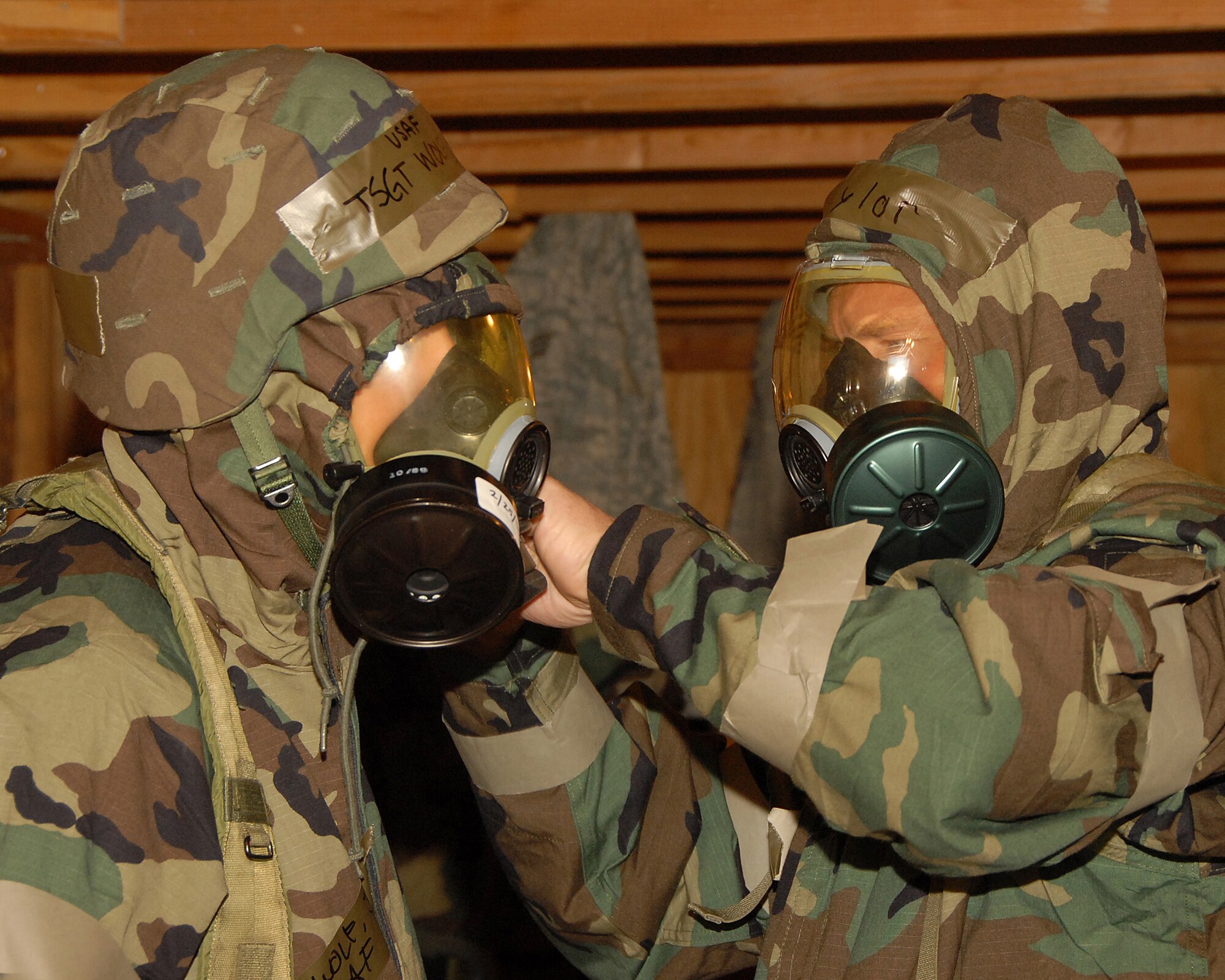 The 130th Engineering Installation Squadron held a super drill at Wendover Air Field, Wendover, Utah June 4-7 in preparation for their upcoming Operational Readiness Inspection. Tech. Sgt. Gregory Taylor assists Tech. Sgt. Jason Wolf with his chemical mask during a MOPP 4 drill. For four days the 130th EIS reenacted several mock chemical attacks where they practiced donning chemical gear, searching for unexploded ordinances and patrolling the area for toxic levels of chemical agents.  U.S. Air Force photo by Staff Sgt. Emily Monson.