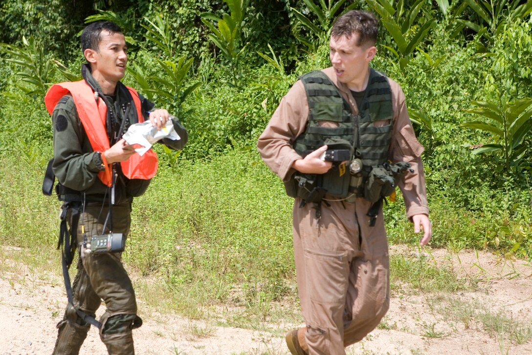 Royal Malaysian Air Force Capt. Mohd Azizi bin Musa and Marine All-Weather Fighter Attack Squadron 225 1st Lt. Steve Bradford move along the road for the final approach to the landing zone to rendevous with the helicopter during a search and rescue exercise here June 28. During their time in the jungle, the pilots faced thick brush, sweltering humidity, poor line of sight and nature's vampires, leeches.