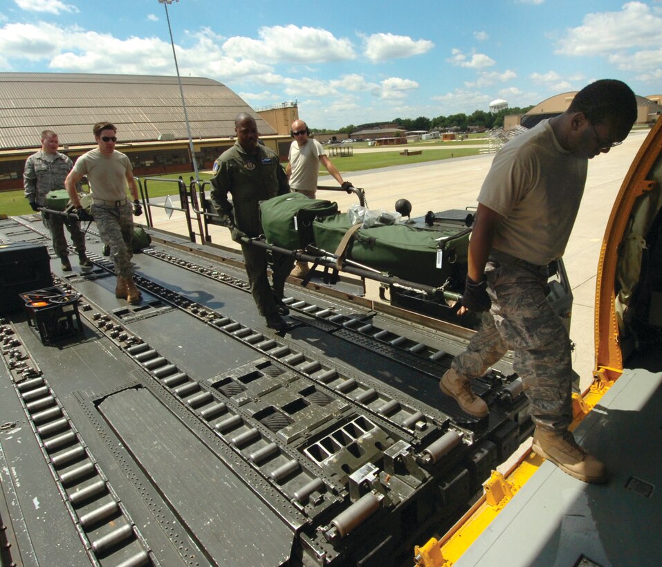 From left: Staff Sgt. Wayland Baker and Technical Sgt. Abraham Lowden, 775th Expeditionary Aeromedical Evacuation Flight medical technicians, follow Tech. Sgt. Willie J. Cooper, 756th Air Refueling Squadron boom operator, center, and Master Sgt. Melvin Anderson, far right, 775th Expeditionary Aeromedical Evacuation Flight medical technician, as they use litters to carry medical equipment off the flat bed of a 89th Aerial Port Squadron 60K Loader onto a 459th Air Refueling Wing KC-135R. The joint-squadron team was staging personal and medical equipment prior to an upcoming aeromedical evacuation mission for wounded warriors Tuesday. (U.S. Air Force photo/ Bobby Jones)
