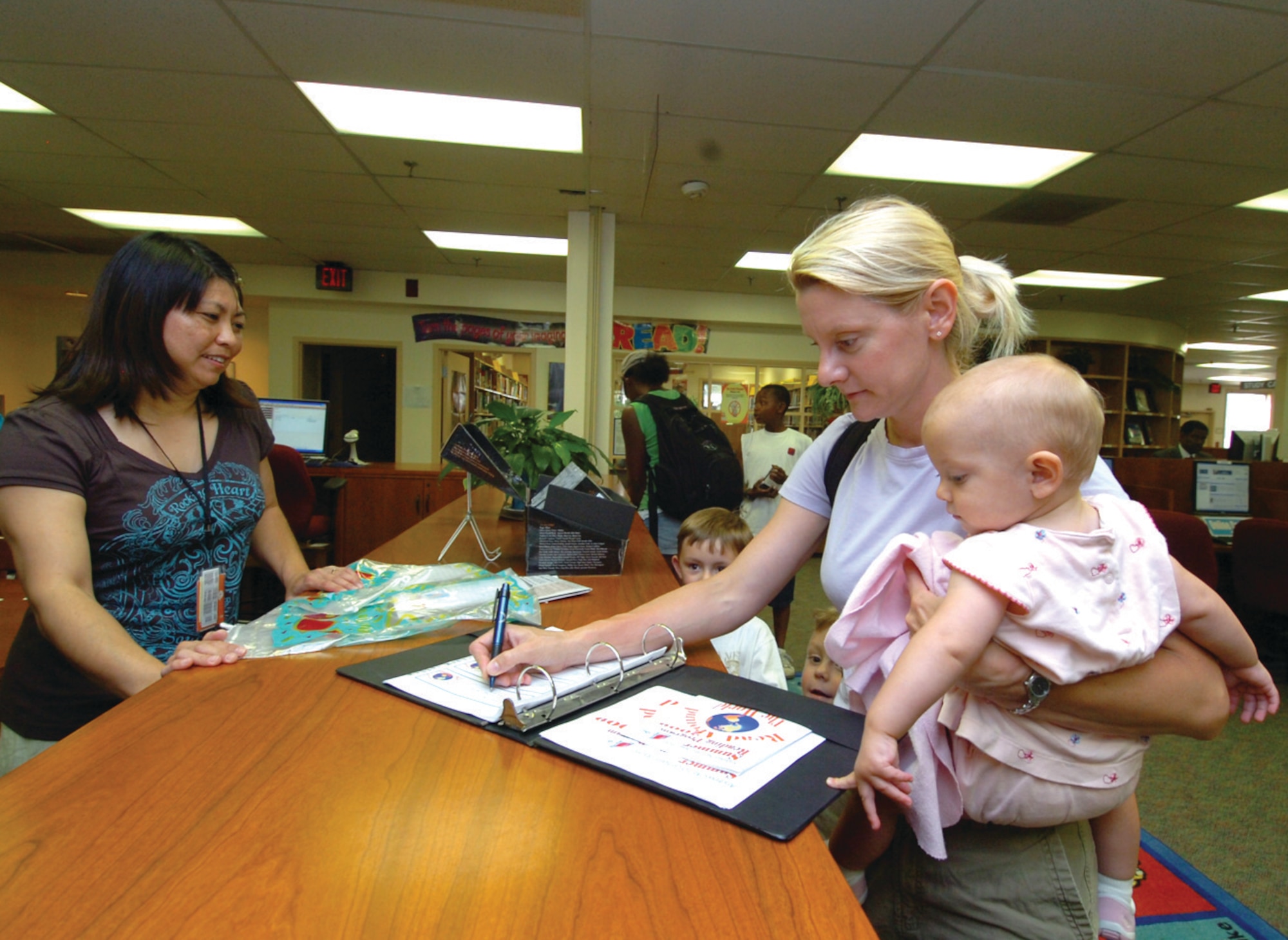 Chikako Shaw, base library aide, left, observes as Julie Huisken, spouse of Col. Timothy Huisken, 779th Medical Group general surgeon, registers for the Summer Reading Program at the base library Monday. The program kicks off a volunteer initiative to encourage members to read as many books as they can until August 12. The program will also highlight a different social event throughout the summer, including Eat-Around-the-World on Thursday; ice cream social on July 20; and a hot dog roast on July 30. At the end of the Summer Reading Program the member who reads the most books will receive a prize. (U.S. Air Force photo/ Bobby Jones)