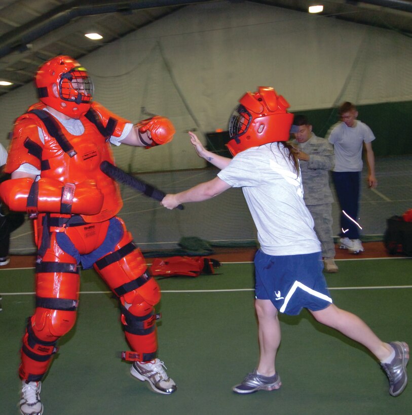 Airman 1st Class Kathleen Lyons, 316th Security Forces Squadron member, right, wards off Staff Sgt. Bradford Stewart, 316 SFS instructor leader, in a padded suit, during an annual expandable baton training session at the West Fitness Center Monday. The two-hour session trains 316 SFS members to use less than lethal force against an attacker. (U.S. Air Force photo/ Bobby Jones)