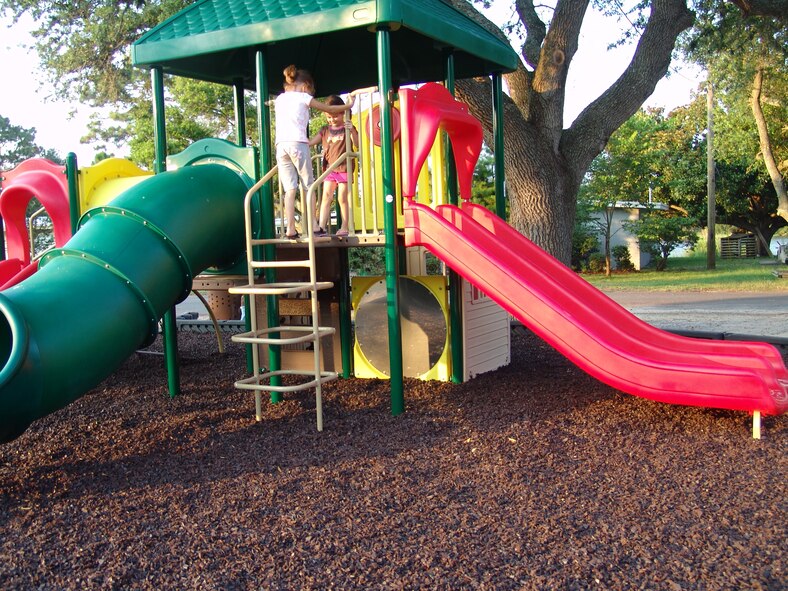 Courtney and Kaitlyn Looney climb on the new playground equipment on Chinquapin Drive.  Three new playgrounds are now open for children living in base housing. (USAF photo/Lois Walsh) 