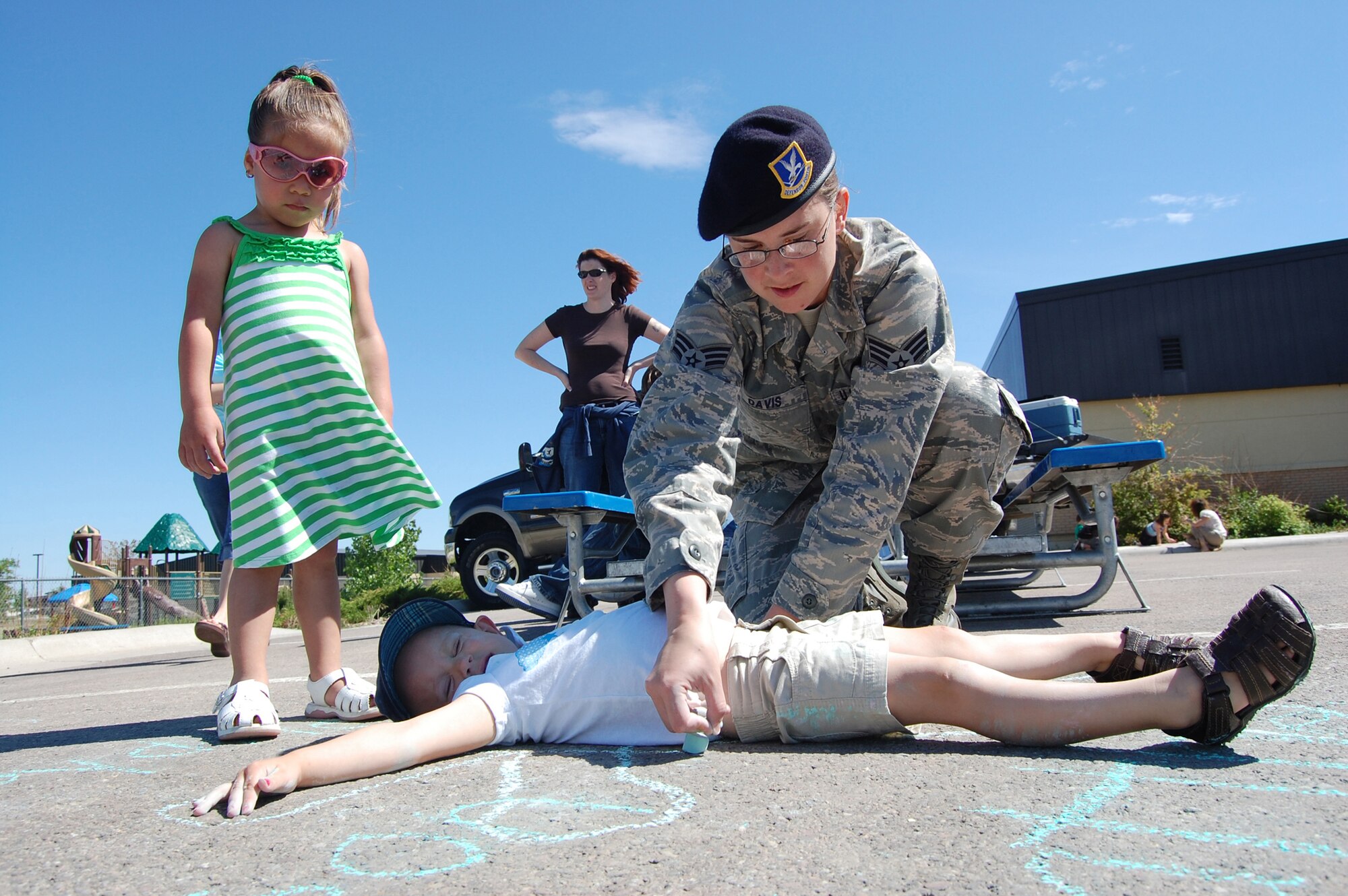 Senior Airman Jessica Davis, 341st Security Support Squadron, draws a chalk line around her daughter, Little Warrior Sydnee, 3,  June 19 as part of the 10th Annual Chalk It Up sidewalk art competition in the Youth Program Center parking lot. In addition to award presentations, participants received a free lunch courtesy of a local restaurant.  (U.S. Air Force photo/Staff Sgt. Marcus McDonald)