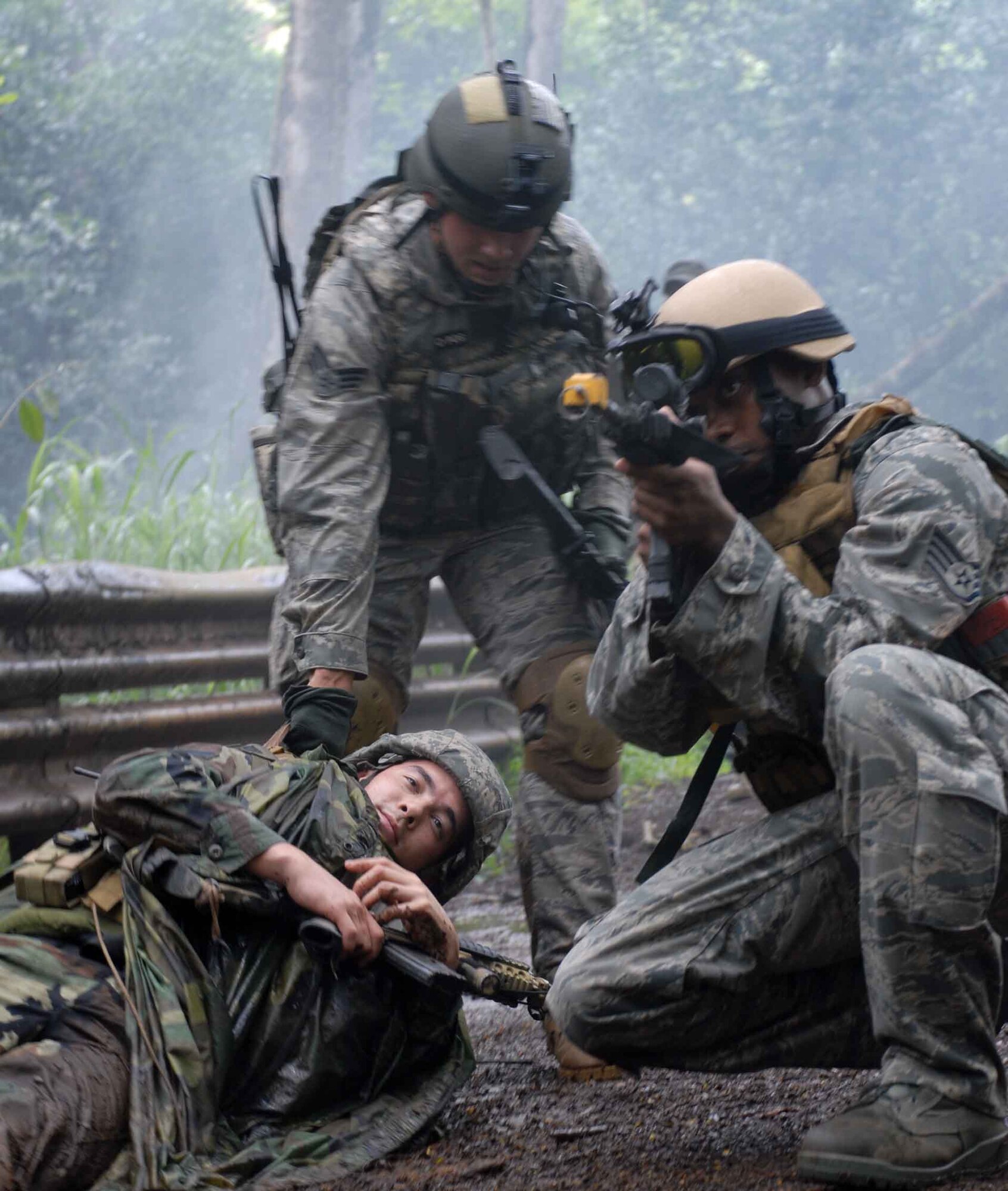 WHEELER ARMY AIR FIELD, Hawaii -- Staff Sgt. Anthony Stewart, 25th Air Support Operations Squadron electrical engineer, provides small arms fire cover for Senior Airman Robert Gains, a Tactical Air Control Party member, while he drags Senior Airman Christopher Lee, a “casualty,” to safety June23. TACPs trained with the Army at Wheeler Army Air Field's East Range June 23-26. Armed with M-16s and basic radio and global positioning system equipment, they made their way through wet brush to find their camping spot and were "ambushed" along the way by pseudo attackers. Training like this ensures safe and reliable wartime readiness for TACPs. (U.S. Air Force photo/Senior Airman Carolyn Viss)
