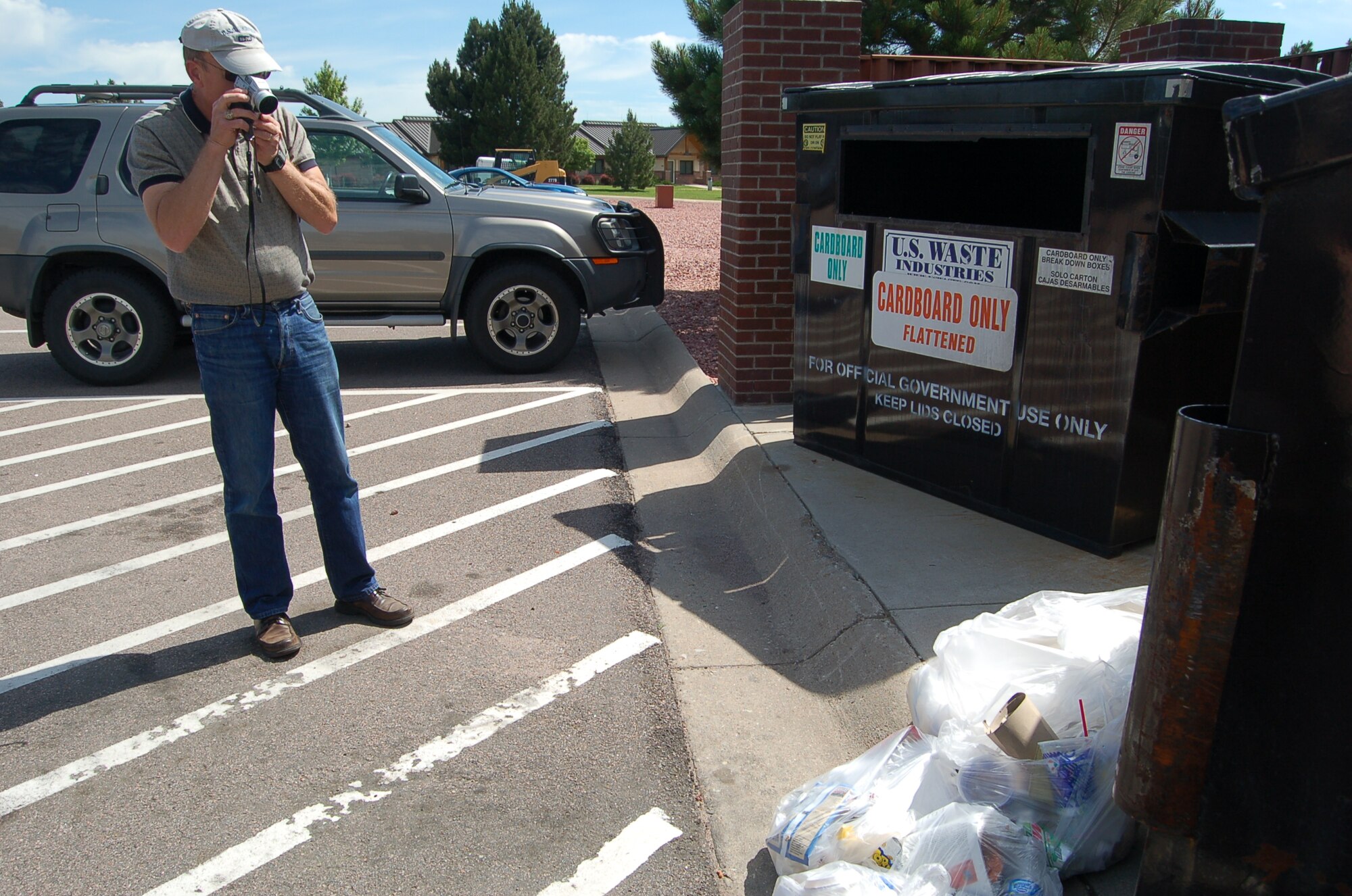 Jerry Lowder, 21st Space Wing Civil Engineer Squadron Natural Assets Flight Environmental Program manager, videos trash that was not separated in recyclable containers at Peterson Air Force Base June 24. Mr. Lowder acted as a solid waste assessor during the wing’s Environment, Safety, and Occupational Health Compliance Assessment and Management Program, also known as ESOHCAMP. The annual self-assessment of environmental practices occurred at Peterson June 22 through June 26 and checked unit compliance of Air Force, state, and federal regulations. Mr. Lowder found 13 aluminum cans, required by regulation to be placed in recyclable dumpster, in the trash dumpster.  (Air Force photo by Thea Skinner)  

