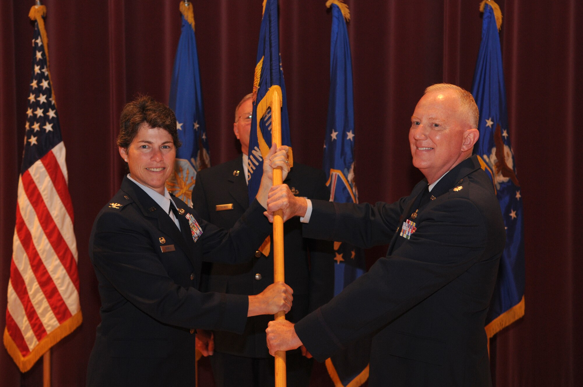 Lt. Col. Alan C. Sierichs, commander of the United States Air Force Band, accepts the United States Air Force Band guidon from Col Elizabeth Borelli, commander of the 11th Operations Group, during a change of command ceremony in Hangar 2 on Bolling Air Force Base, June 30. The ceremony marked Colonel Layendecker’s final day as commander of the U.S. Air Force Band.   (U.S. Air Force photo by Senior Airman Sean Adams)