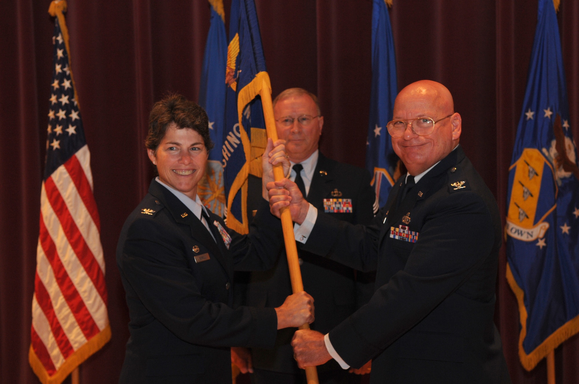 Col. Elizabeth Borelli, commander of the 11th Operations Group, accepts the United States Air Force Band guidon from Col. Dennis M. Layendecker during a change of command ceremony in Hangar 2 on Bolling Air Force Base, June 30. The ceremony marked Colonel Layendecker’s final day as commander of the U.S. Air Force Band.  (U.S. Air Force photo by Senior Airman Sean Adams)