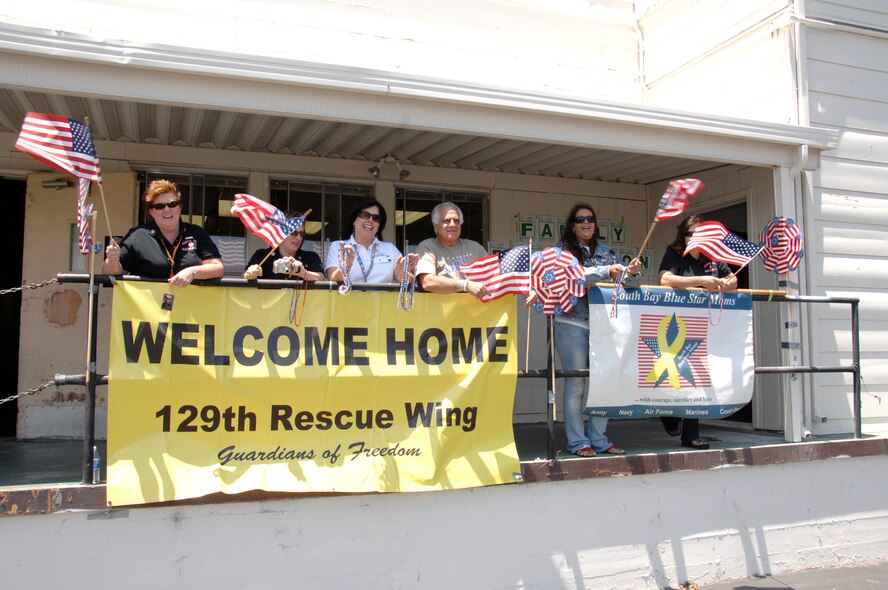 129th Rescue Wing Family Readiness volunteers and the Blue Star Moms display a welcome home banner to greet 129th Rescue Wing Airmen returning to Moffett Federal Airfield, Calif., June 13 from a 40-day deployment to Djibouti. (Air National Guard photy by Master Sgt. Dan Kacir)(RELEASED)