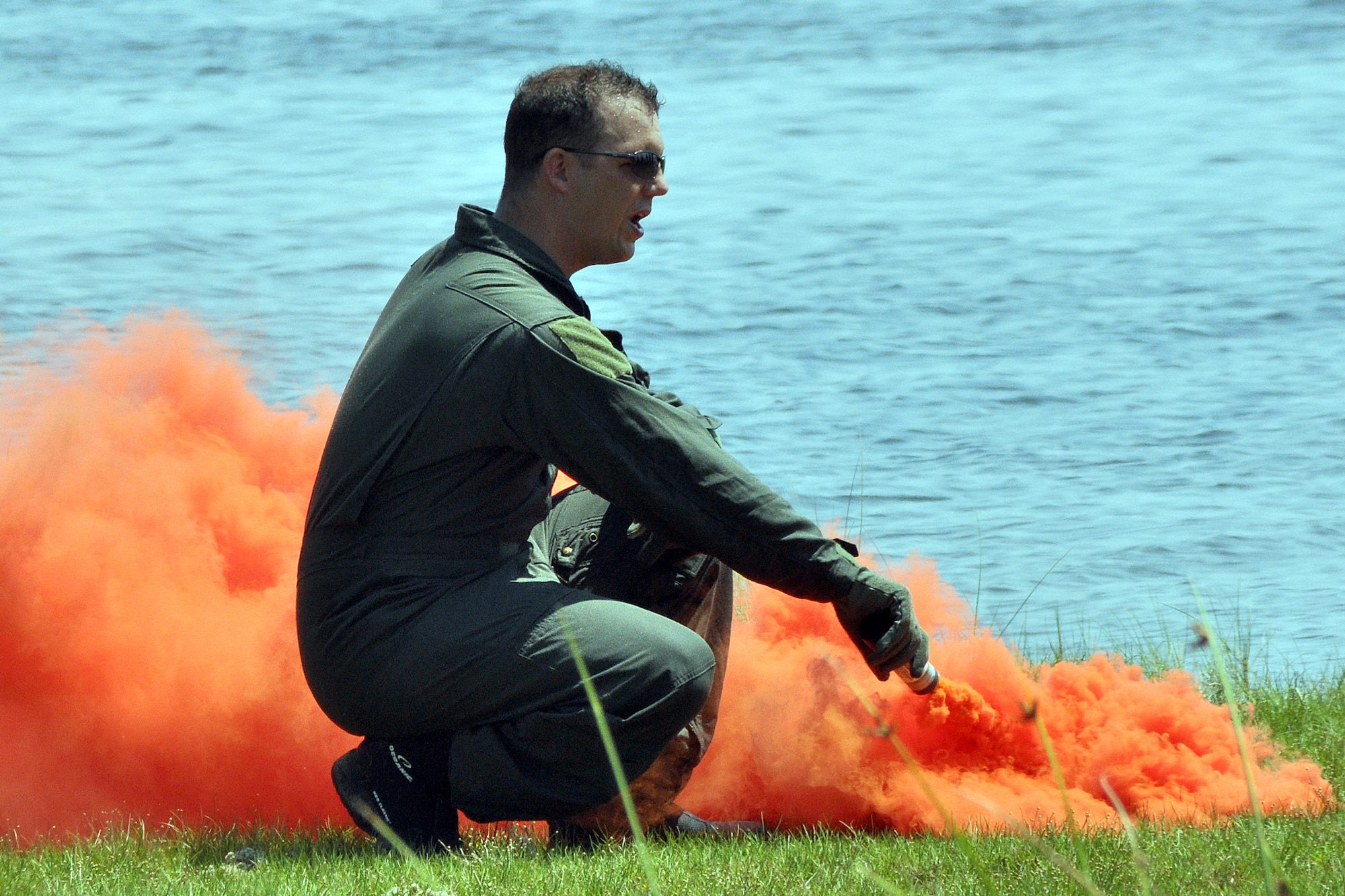EGLIN AIR FORCE BASE, Fla. -- Staff Sgt. Benjamin Rosciglione, 33rd Operations Support Squadron, demonstrates the proper way to use a smoke flare during a Survival Evasion Resistance Escape training exercise for pilots June 26 at Post’l Point. The training was a water continuation course which included a parachute drag, raft living procedures and recovery hoist training. Pilots must undergo continuation training every three years. (U.S. Air Force photo/ Airman Anthony Jennings)