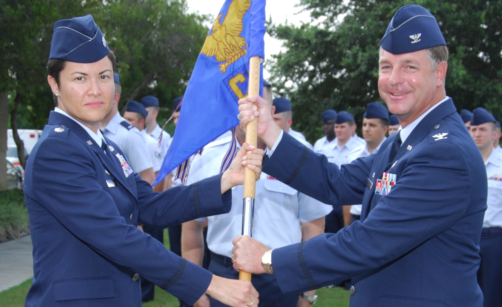 Col. David Zeh, 325th Mission Support Group commander, presents the guidon to Lt. Col. Clorinda Trujillo as she takes command of the 325th Communications Squadron.  The change of command ceremony took place June 29 in Bldg. 650.   Colonel Trujillo took over command from Maj. Jon Hannah.  (U.S. Air Force photo/Lisa Norman