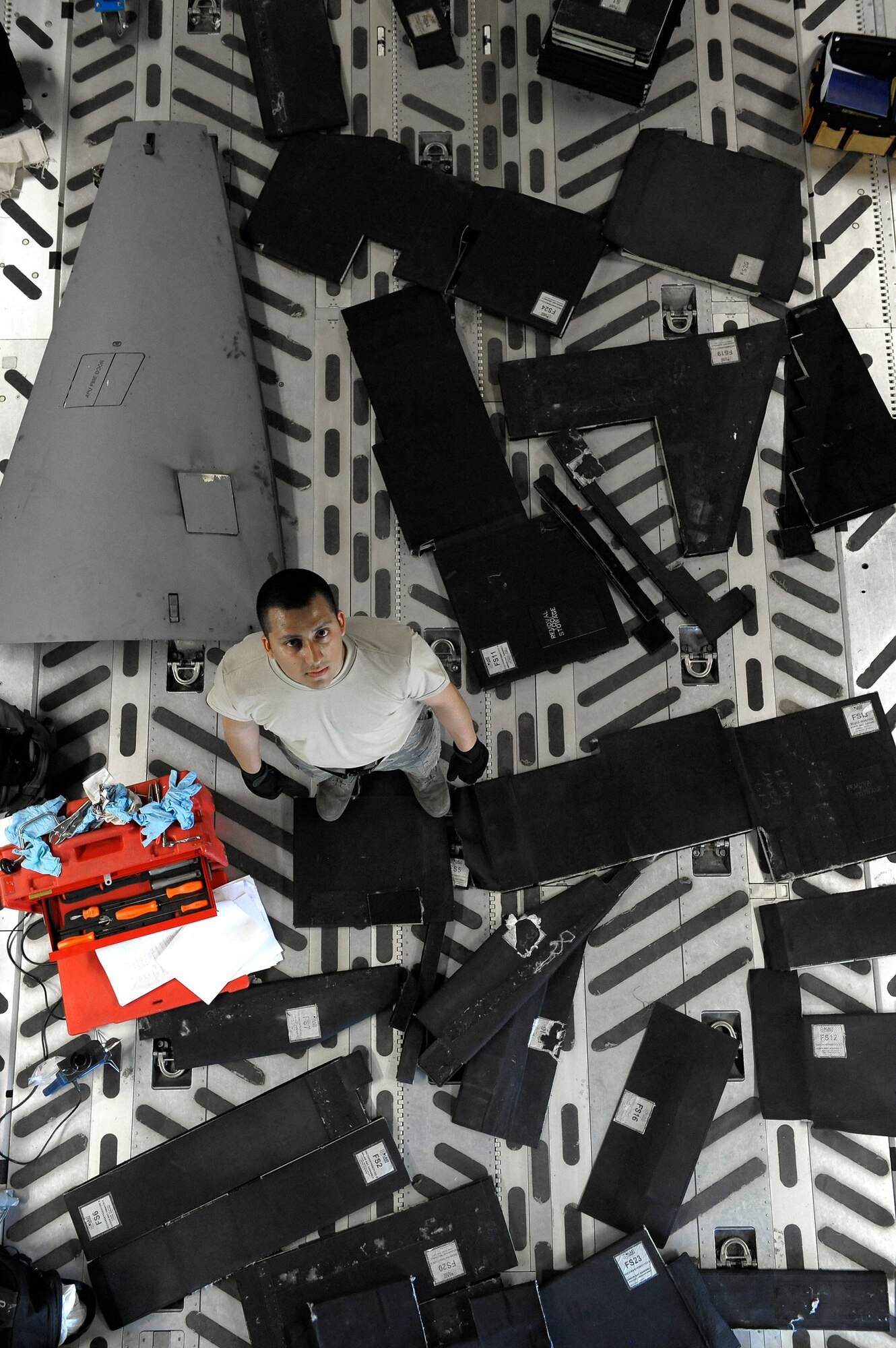 ELMENDORF AIR FORCE BASE, Alaska -- Airman 1st Class Manuel Pakilla stands down below surrounded by pieces of bulletproof mats that will be used to surround the cockpit area June 29. Padilla is part of an 11-man crew that is preparing for the Air Mobility Command Rodeo at McChord Air Force Base, Wash., July 18-26. (U.S. Air Force photo/Master Sgt. Keith Brown)
