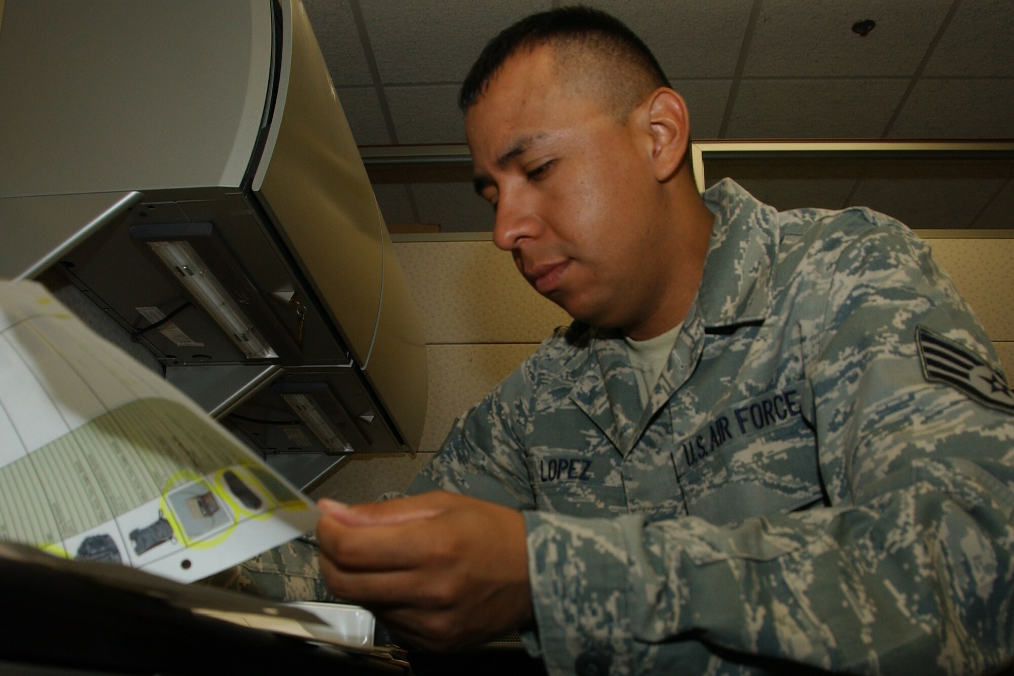 Staff Sgt. Joe Lopez, a wing deployment center deployment manager, looks over a list of required mobility equipment for an upcoming deployment. (U.S. Air Force photo by Staff Sgt. Brian Hill)