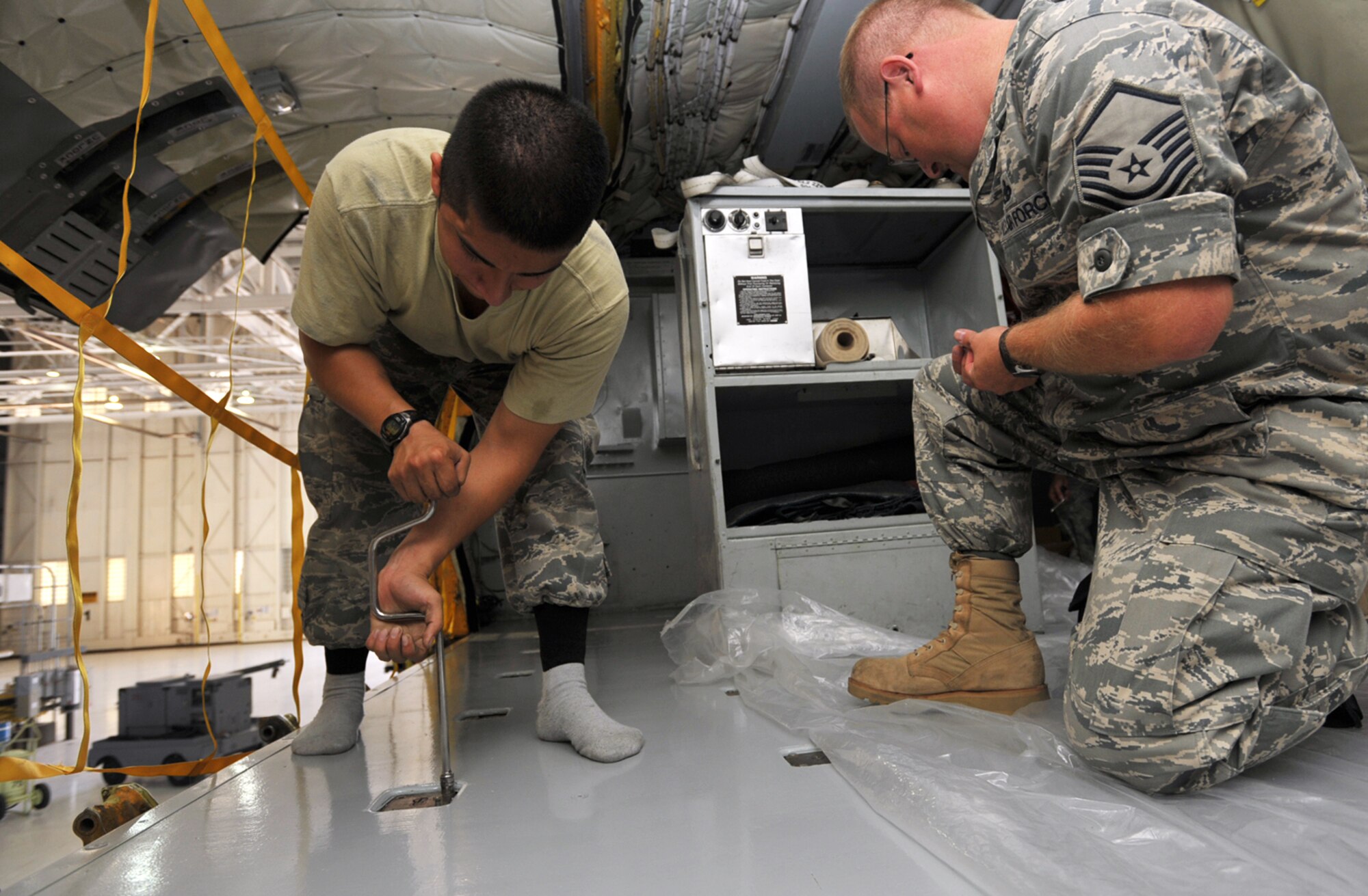 Senior Airman Gilberto Rodriguez-Martinez (on left) works in his socks and Master Sgt. Al Ryder steps on plastic to protect a new coat of paint to the floor of a KC-135 Stratotanker scheduled for competitions at Air Mobility Rodeo 2009. Both maintainers are assigned to a "blended" team of Reserve and Regular (active-duty) Airmen preparing to represent McConnell Air Force Base, Kan., as a total force at the biennial readiness competition. Sergeant Ryder is a Reservist assigned to the 931st Aircraft Maintenance Squadron. Airman Rodriguez-Martinez is an active-duty Airman assigned to the 22nd Aircraft Maintenance Squadron. (U.S. Air Force photo/Tech. Sgt. Jason Schaap)