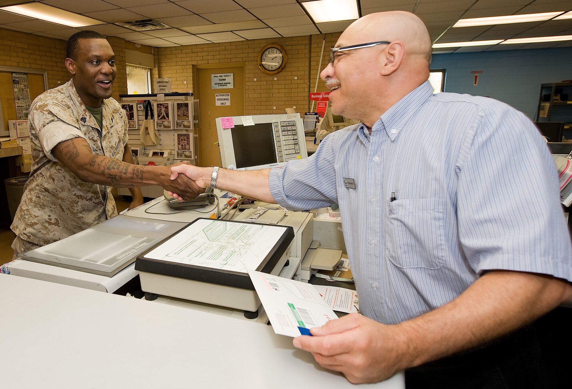 Marine Sgt. Tristin Allums, deployed to the 436th Aerial Port Squadron as a Marine liaison, shakes the hand of fellow Marine Fernando Martin, postal service clerk at Dover Air Force Base. Mr. Martin served in the Vietnam Conflict in 1968 and called his meeting with Sergeant Allums, the old devil dog meeting the new devil dog. (U.S. Air Force photo/Jason Minto)