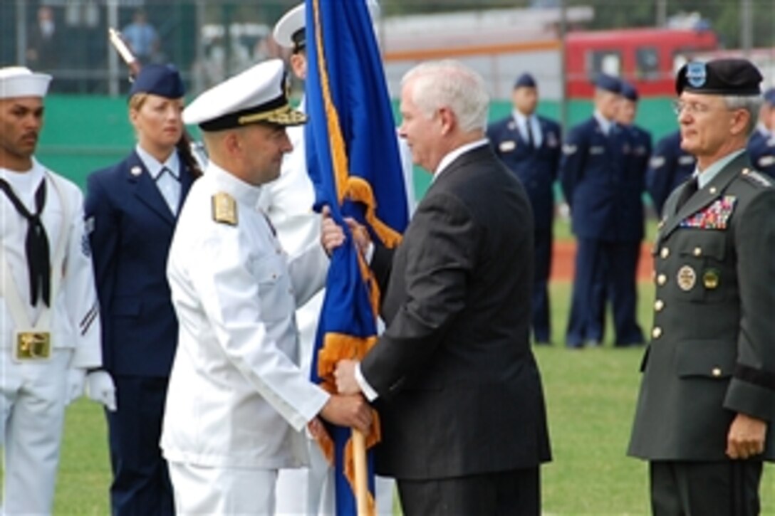 Defense Secretary Robert Gates presents the U.S. European Command guidon to Navy Adm. James Stavridis during a change of command ceremony in Stuttgart, Germany, June 30, 2009. Stavridis, who replaces Army Gen. John Craddock, will also assume responsibilities as NATO supreme allied commander, Europe, in a ceremony July 2 in Mons, Belgium. 