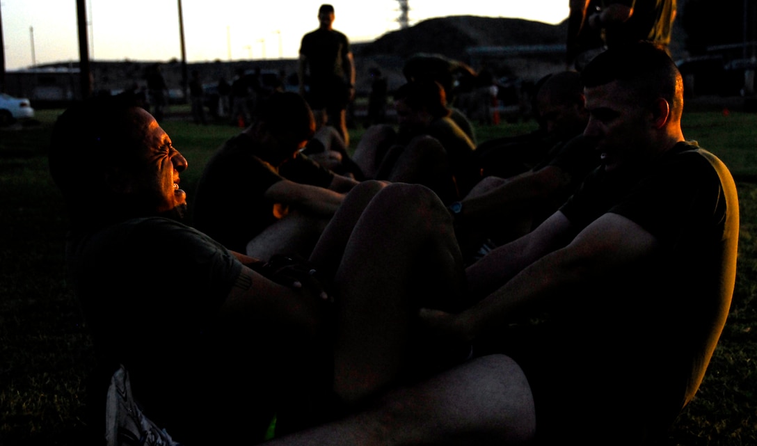 Gunnery Sgt. Jimmy Foster, station telephone chief, holds station emergency aircraft recovery runway supervisor Staff Sgt. Ruben Ogaz’s legs while he does a crunch at Ramada Field at the Marine Corps Air Station in Yuma, Ariz., during a Headquarters and Headquarters Squadron physical fitness test June 30, 2009. Active duty Marines are required to run two PFTs annually, one before June 30 and one before Dec. 31.